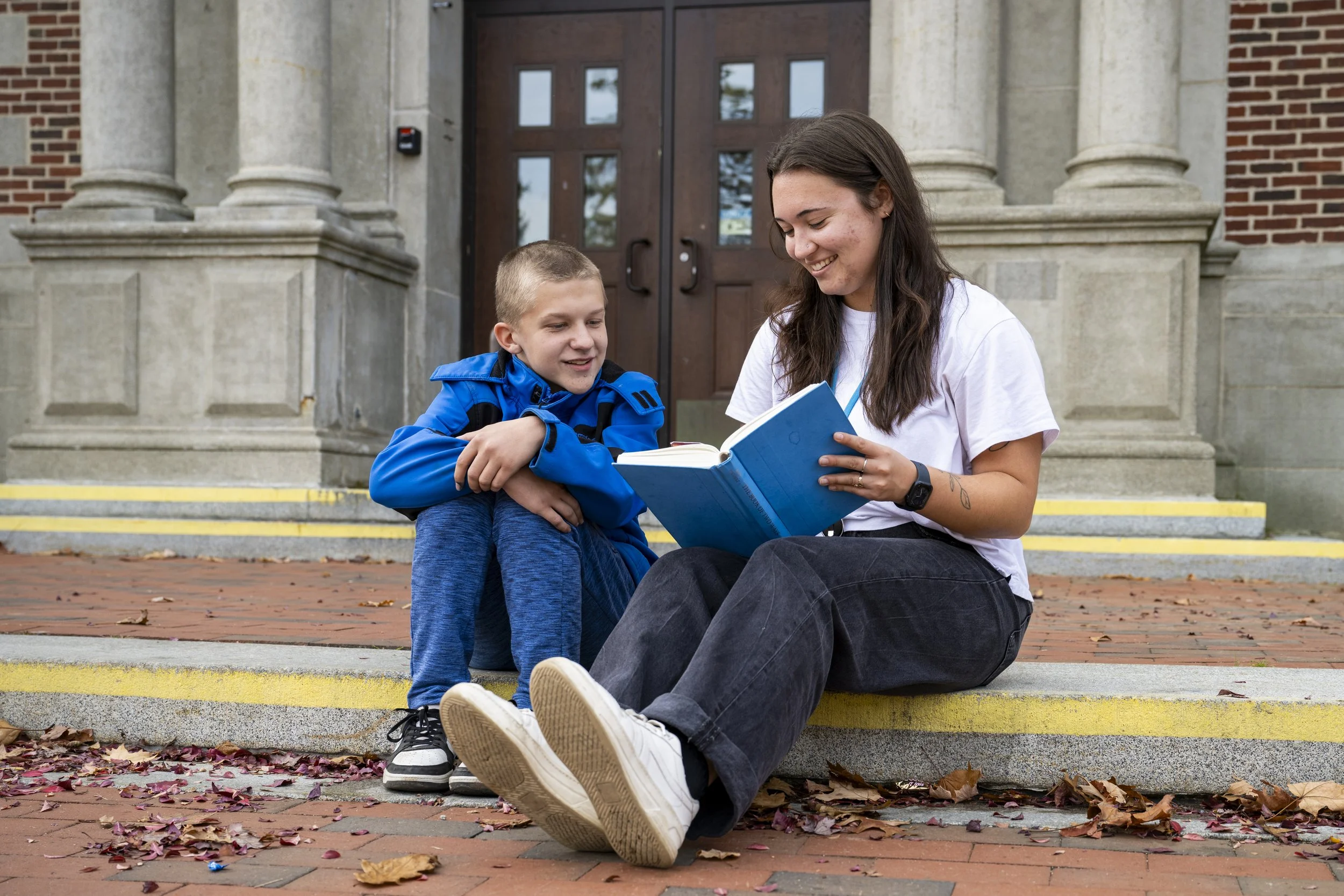 A student and BHP read together in front of a school