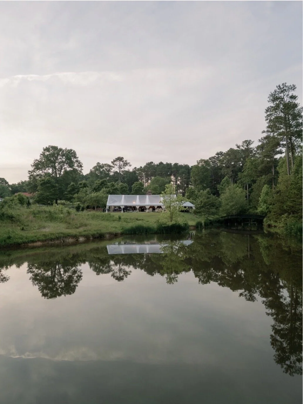 Inn at serenbe landscape with a pond and wedding reception tent