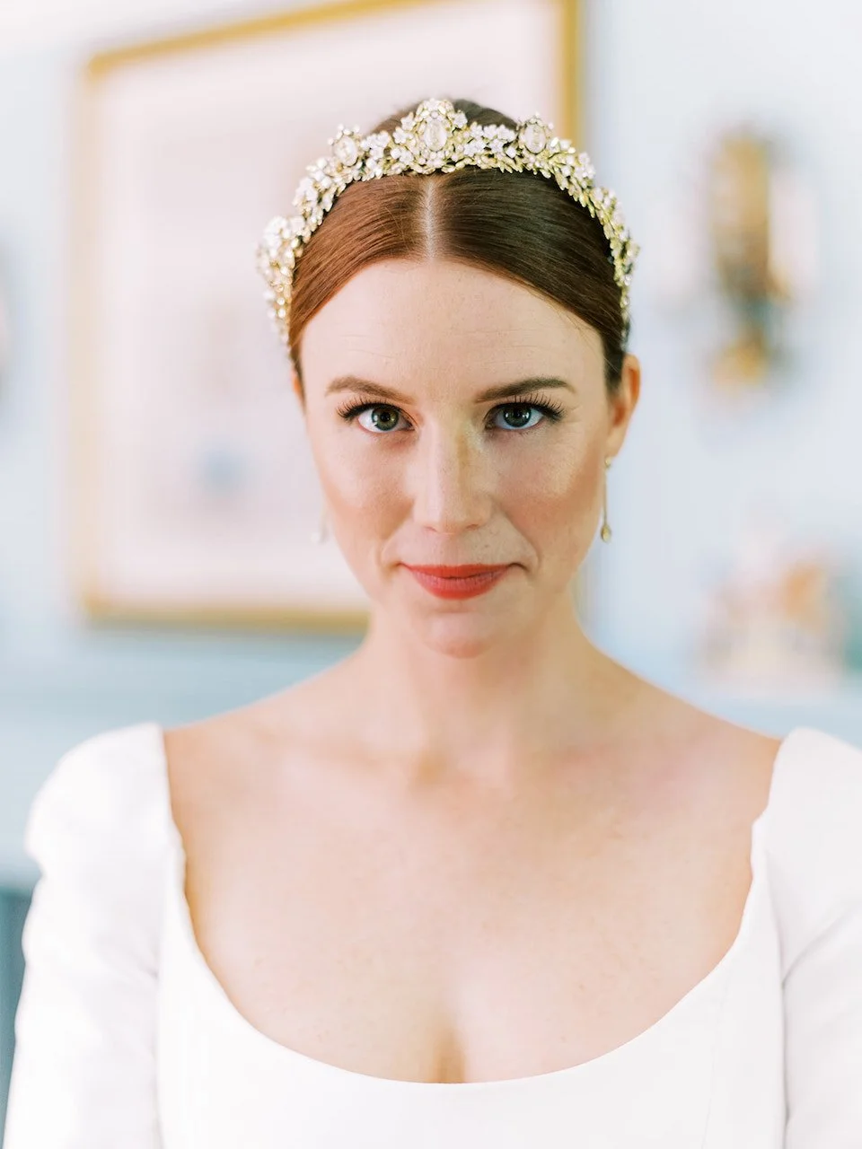 beautiful bride with red hair swept back into a bun with pops of color for her makeup in her wedding gown
