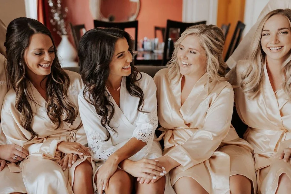 bride and bridesmaids laughing in a bridal suite before they get into their formal dresses