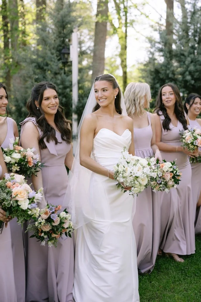 bridesmaids in a mauve gown walking beside the bride in a stunning white gown