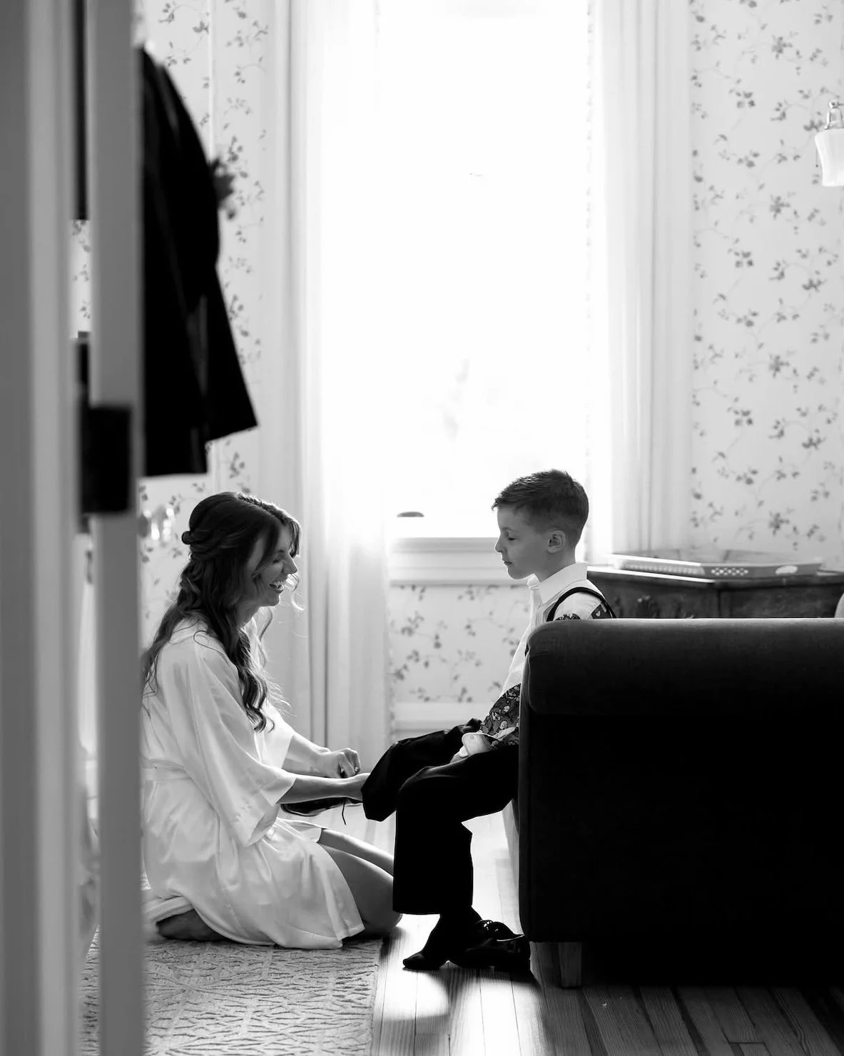 bride and young son share a touching moment as she helps get him dressed