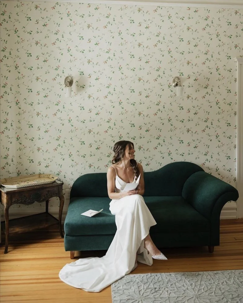 professional photo of a bride sitting on a green chaise lounge in the bridal suite at hills & dales estate