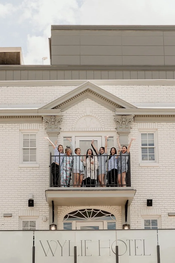 bride and bridesmaids standing on the balcony of the wylie hotel in atlanta ga