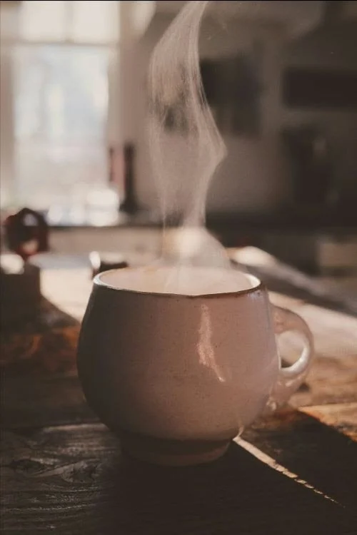 steaming pottery cup of a hot drink