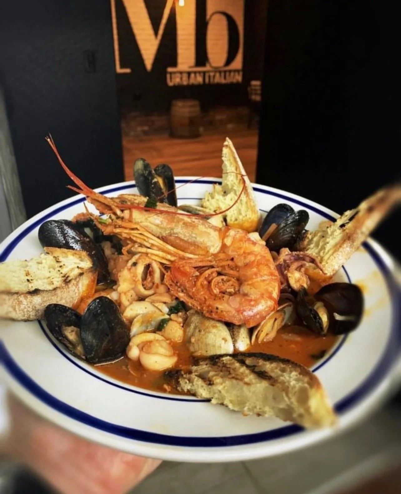 Seafood dish with shrimp, mussels, fish, and bread in a bowl