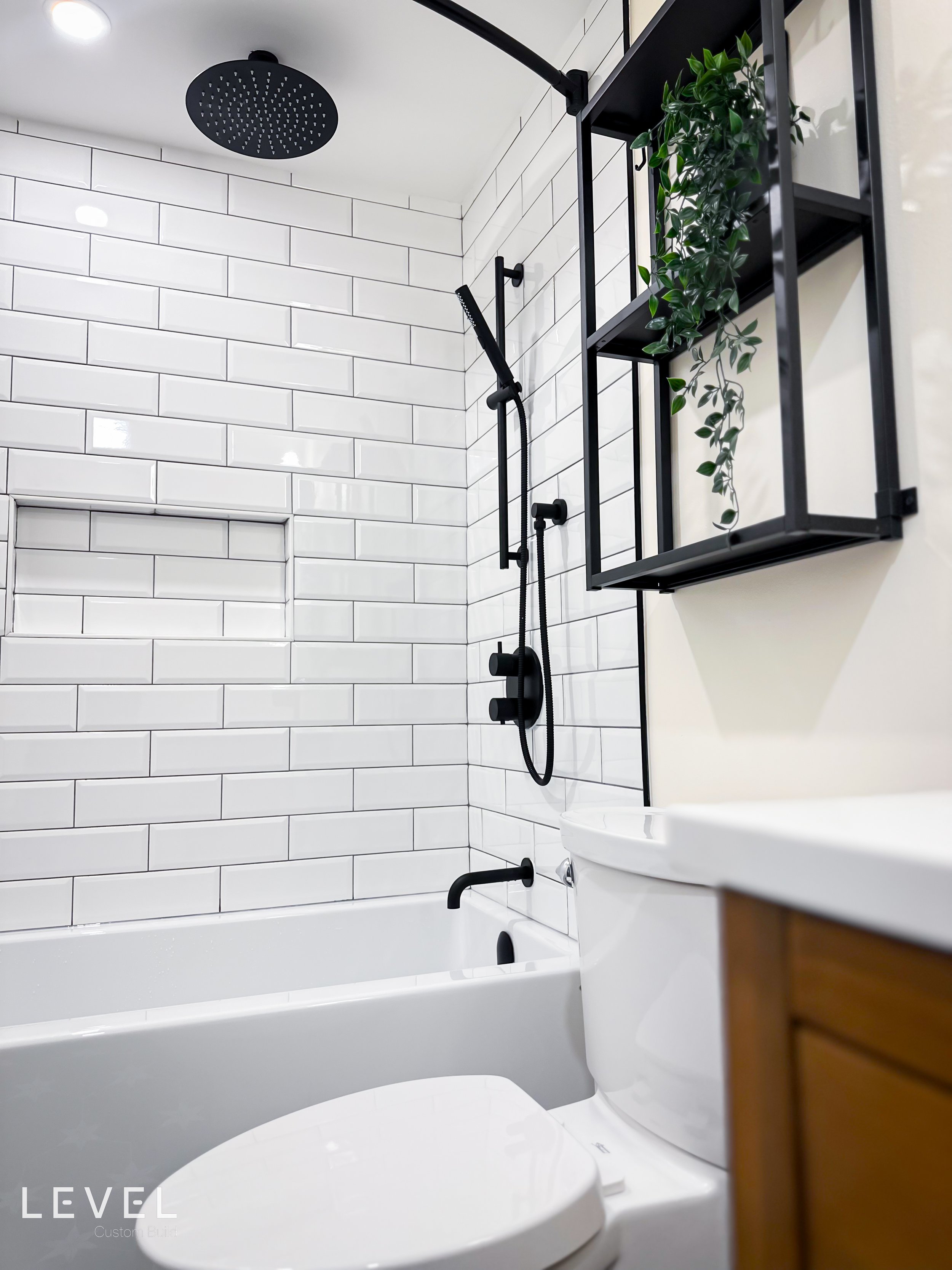 Our clients wanted to give their condo bathroom a simple update. The idea was to keep things neutral, so we went with black and white theme and a medium wood vanity to break up the neutral color palette. The result was a simple and comfortable update