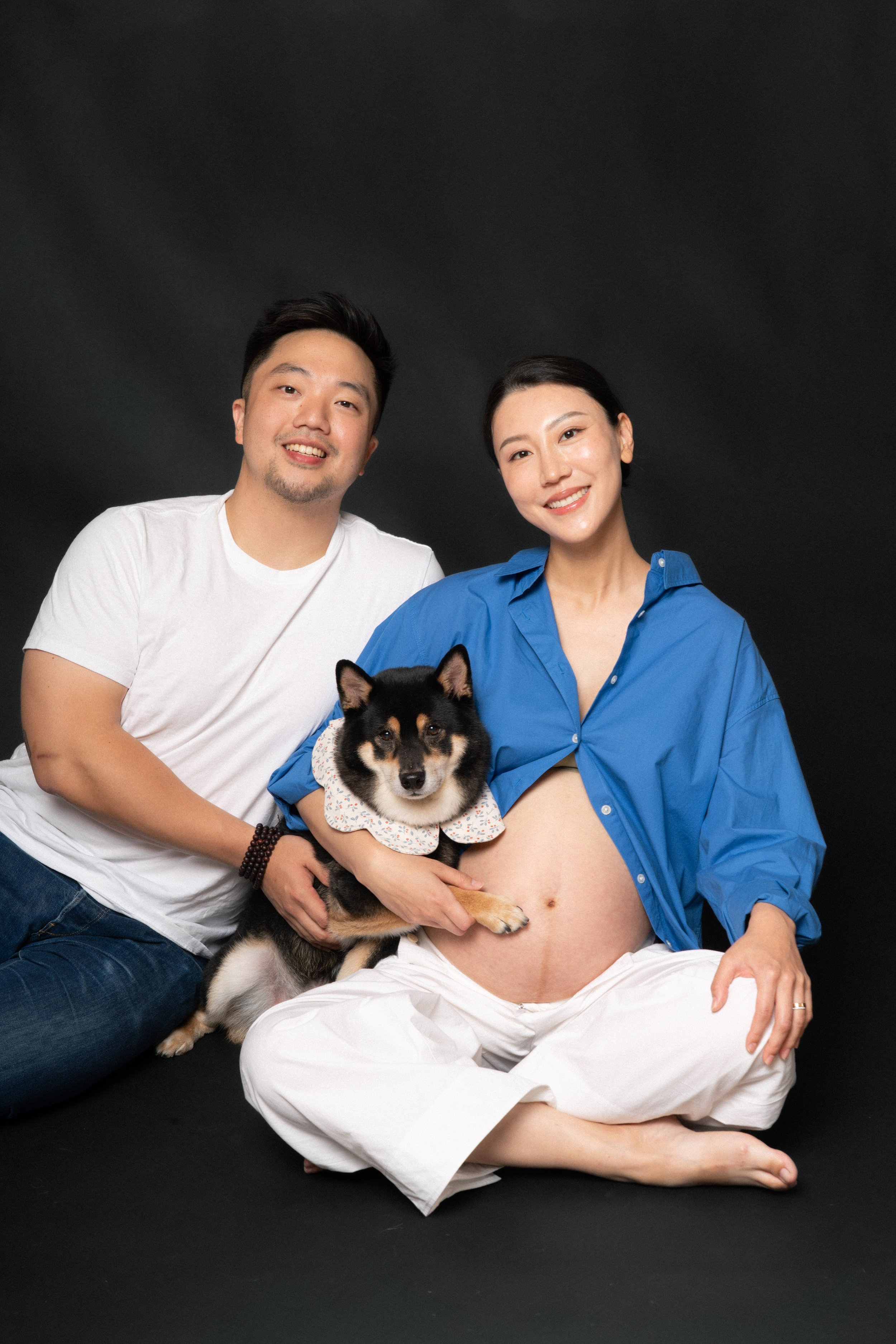 Sitting pregnant Cloris with husband Eric and Jesse the Shiba Inu in soft studio light, NYC maternity session