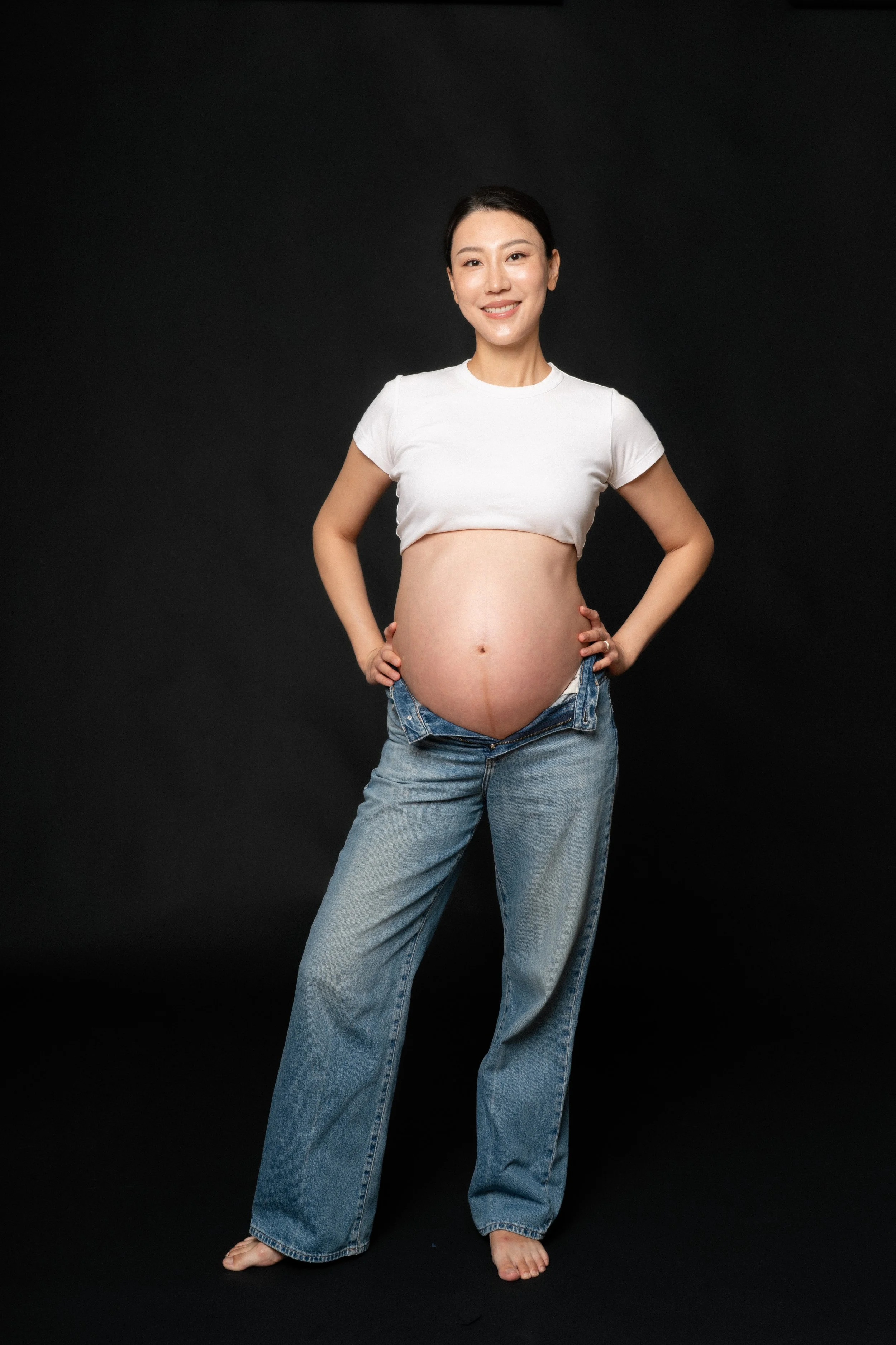 Full-length maternity portrait of Cloris against a neutral backdrop