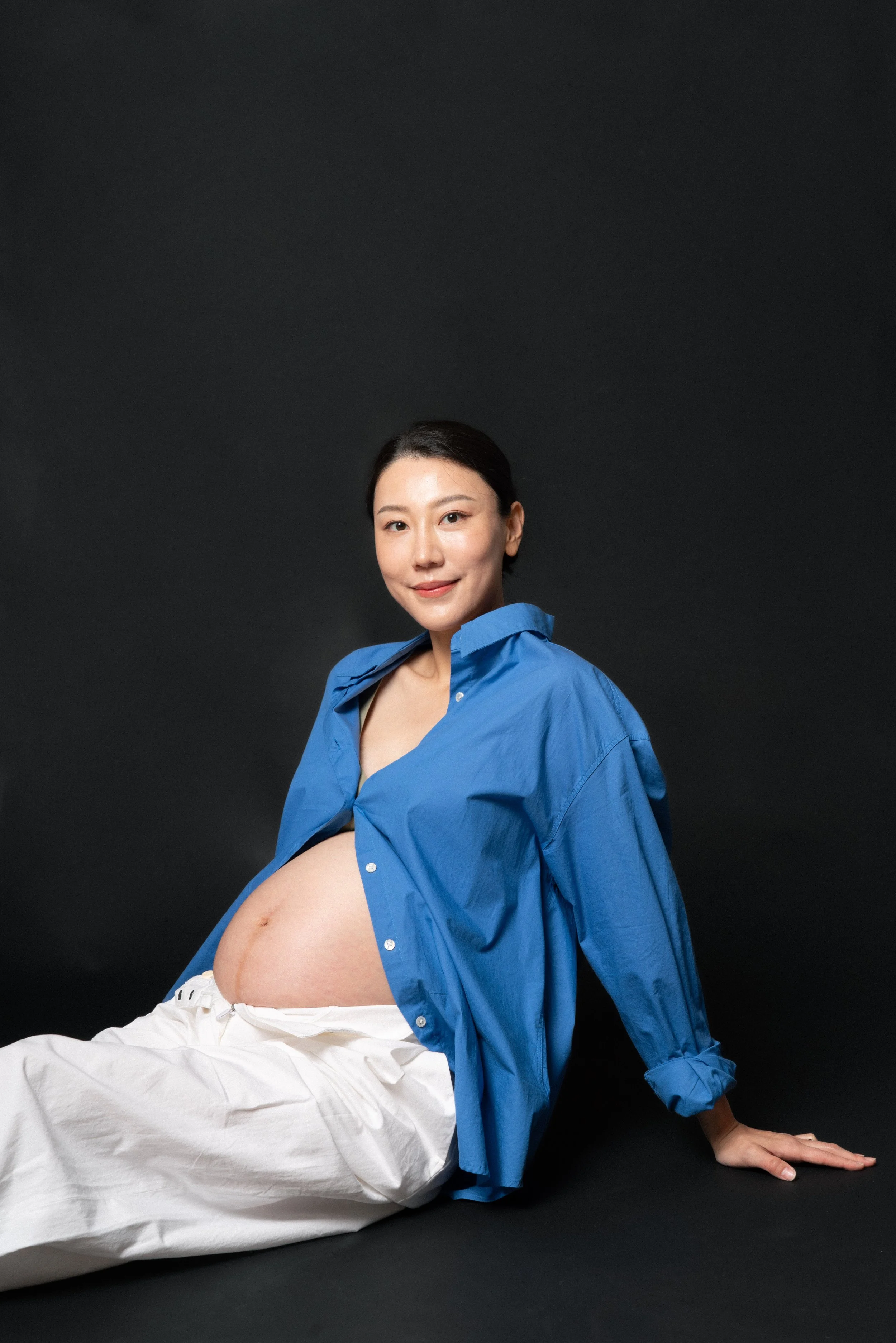 Cloris sitting on the floor and showing off her baby bump in soft studio light