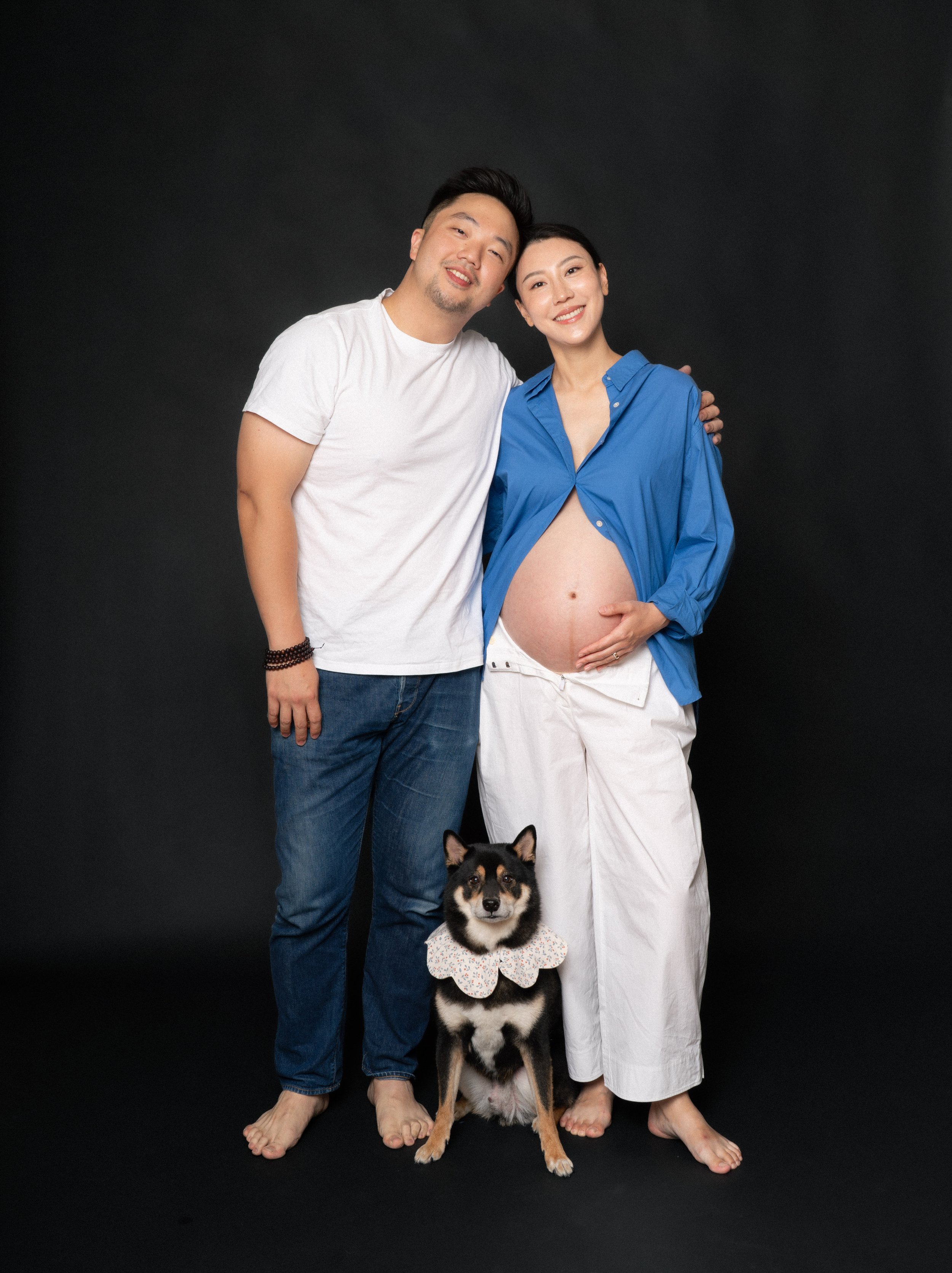 Full length pregnant Cloris with Eric and Jesse the Shiba Inu in soft studio light, NYC maternity session