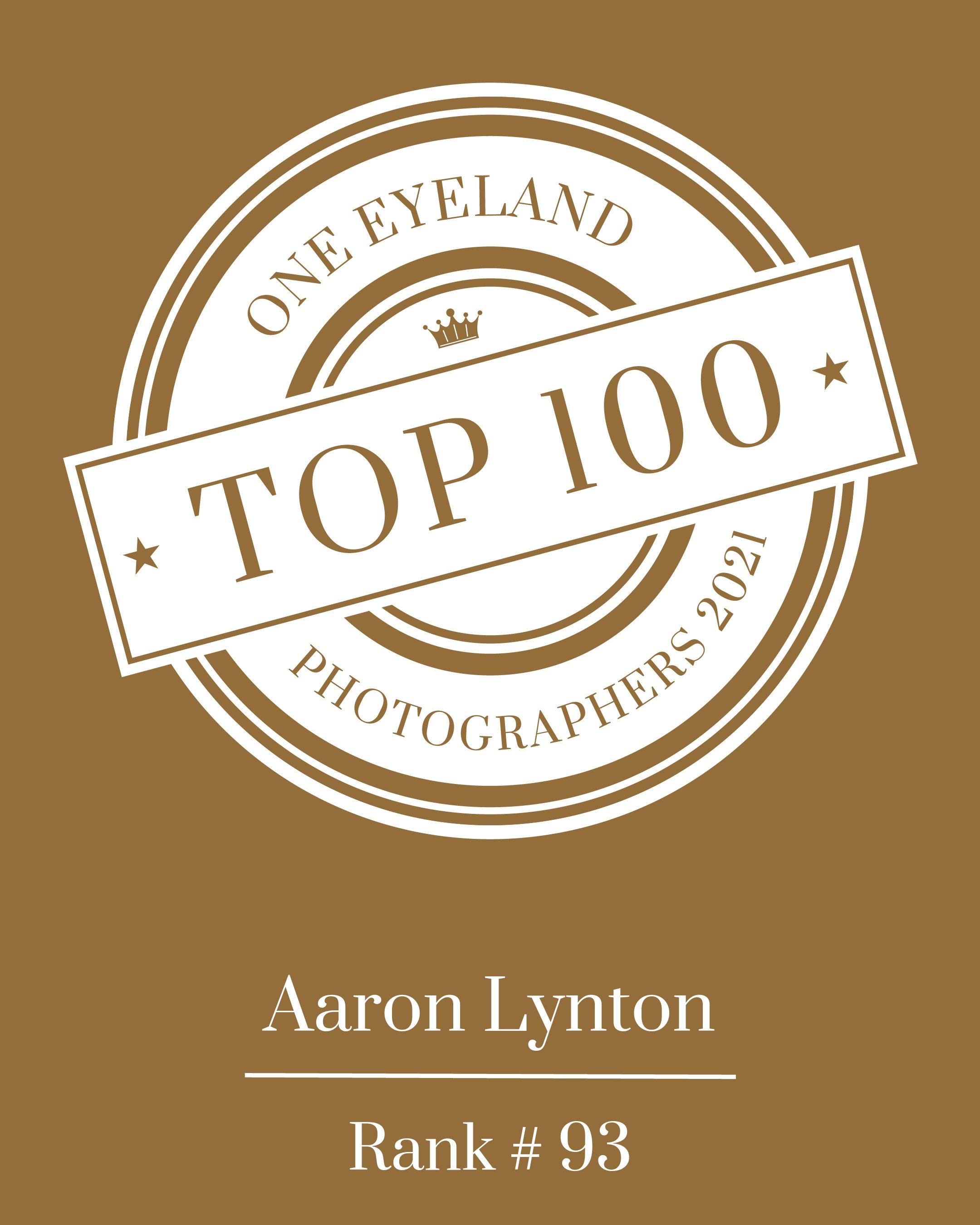 Badge design with white and brown text, featuring a crown, stating 'One Eyeland Photographers 2021 Top 100', with the name 'Aaron Lynton' and rank '#93' at the bottom.