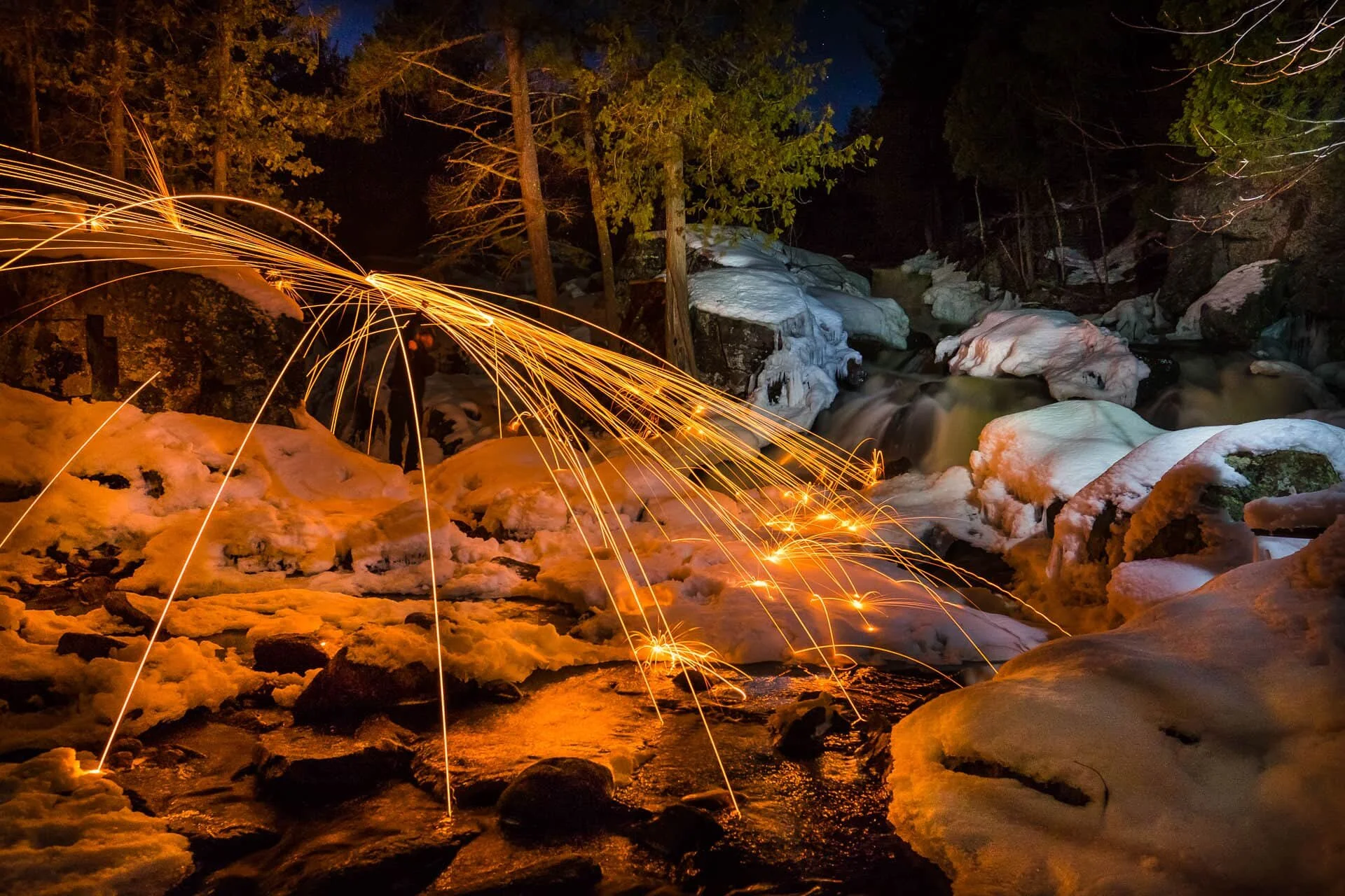 Steel wool spinning — full spread of sparks over frozen creek