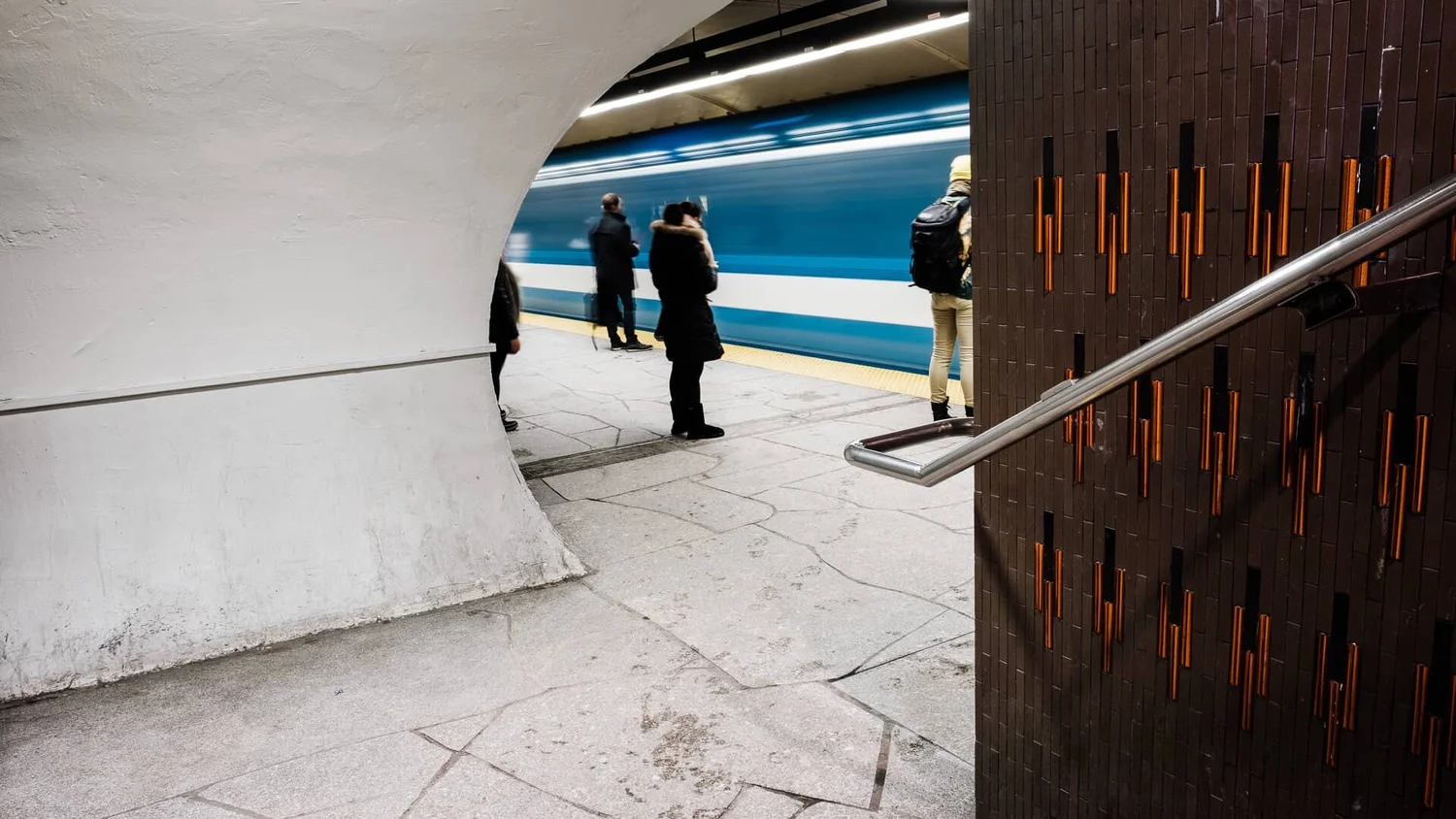 Métro Beaubien — white arch, blurred figures, orange tile wall detail