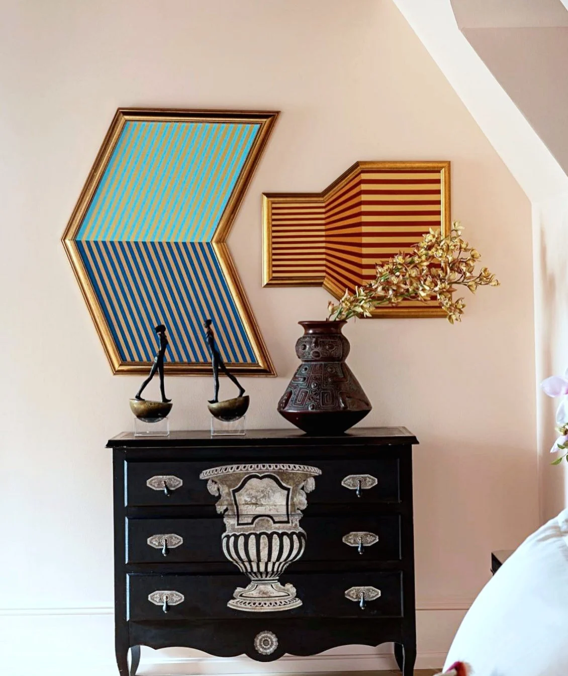 Two geometric artworks displayed above a decorative chest in a residential interior.