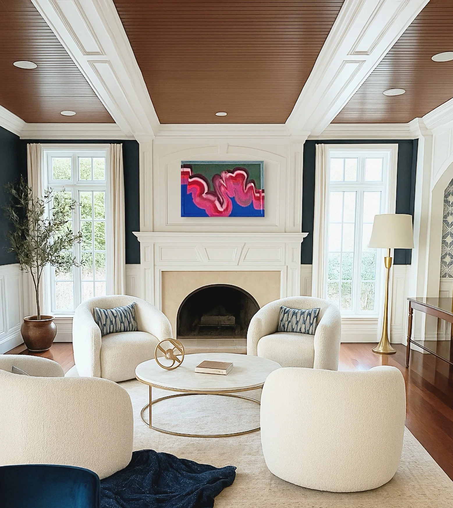 Living room with white chairs, a marble coffee table, a fireplace, large windows, a gold floor lamp, a potted plant, abstract artwork above the fireplace, and hardwood floors.