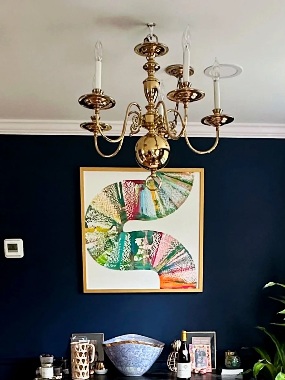 Contemporary artwork displayed against a dark blue wall in a residential interior.