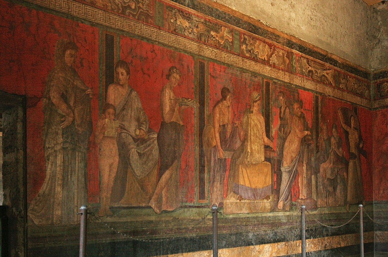 Red-ground Roman fresco showing figures in the Villa of the Mysteries at Pompeii.