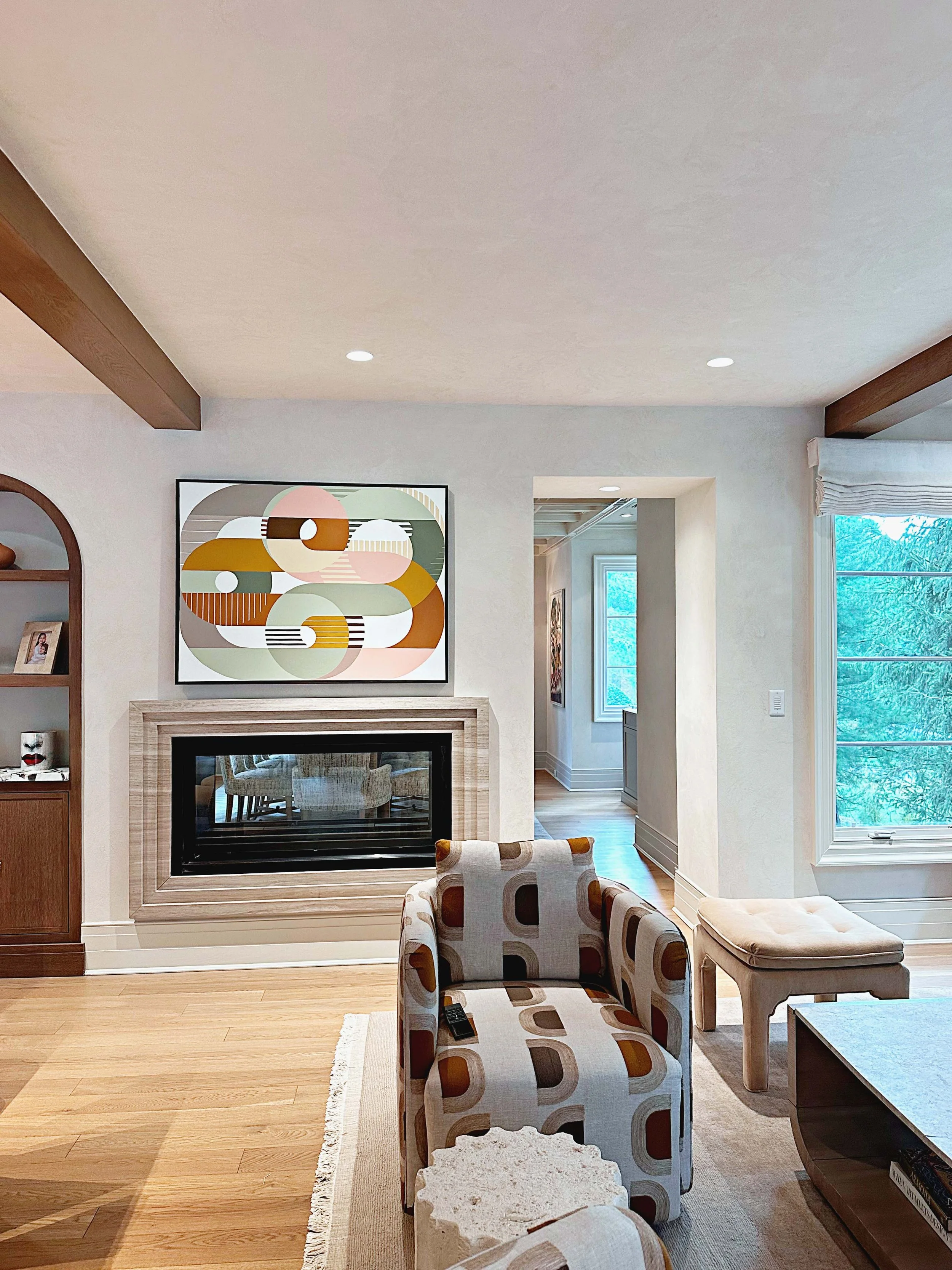 Geometric contemporary artwork above a fireplace in a naturally lit residential living room.