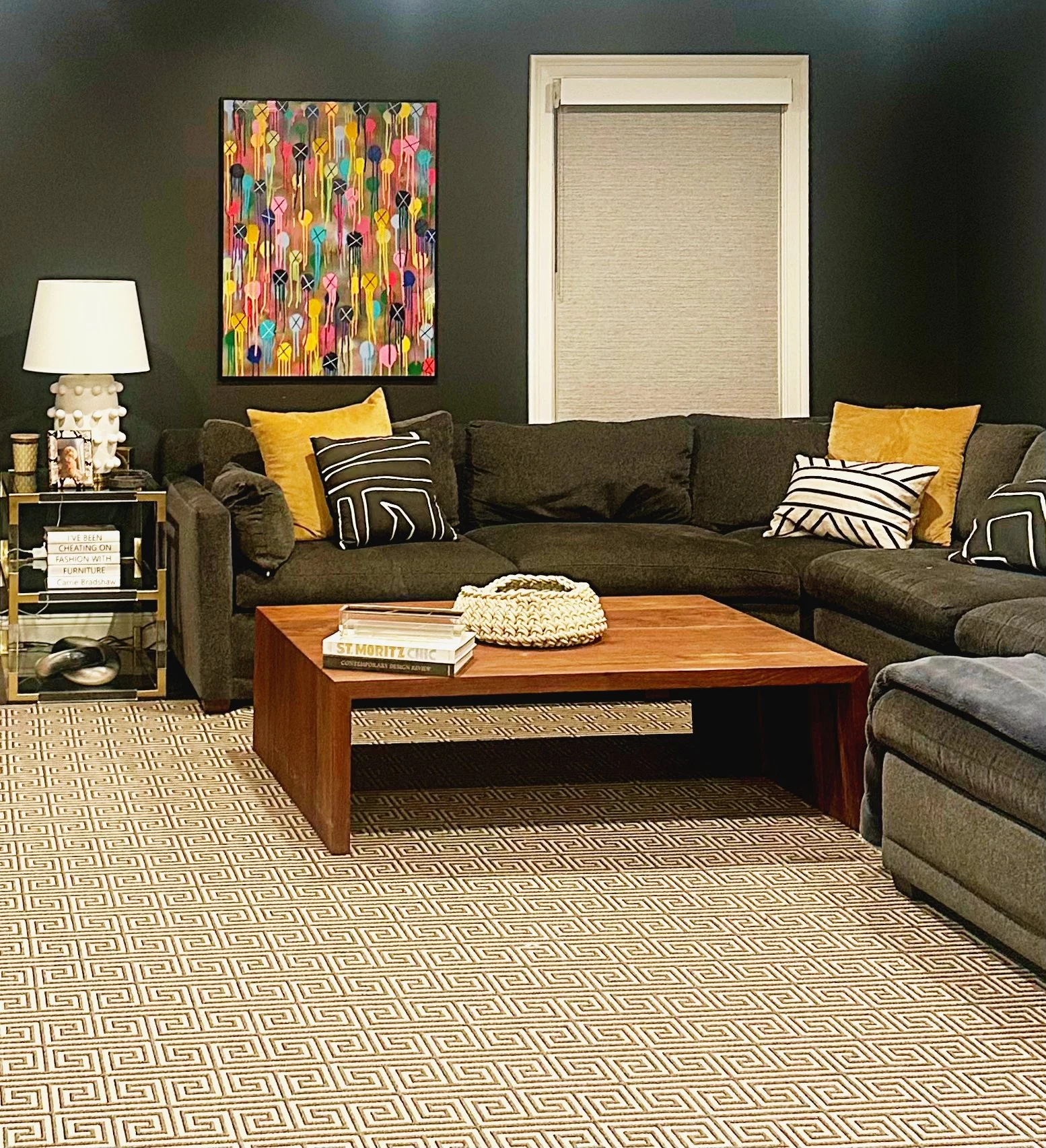 Colorful contemporary painting above a dark sectional sofa in a residential living room.