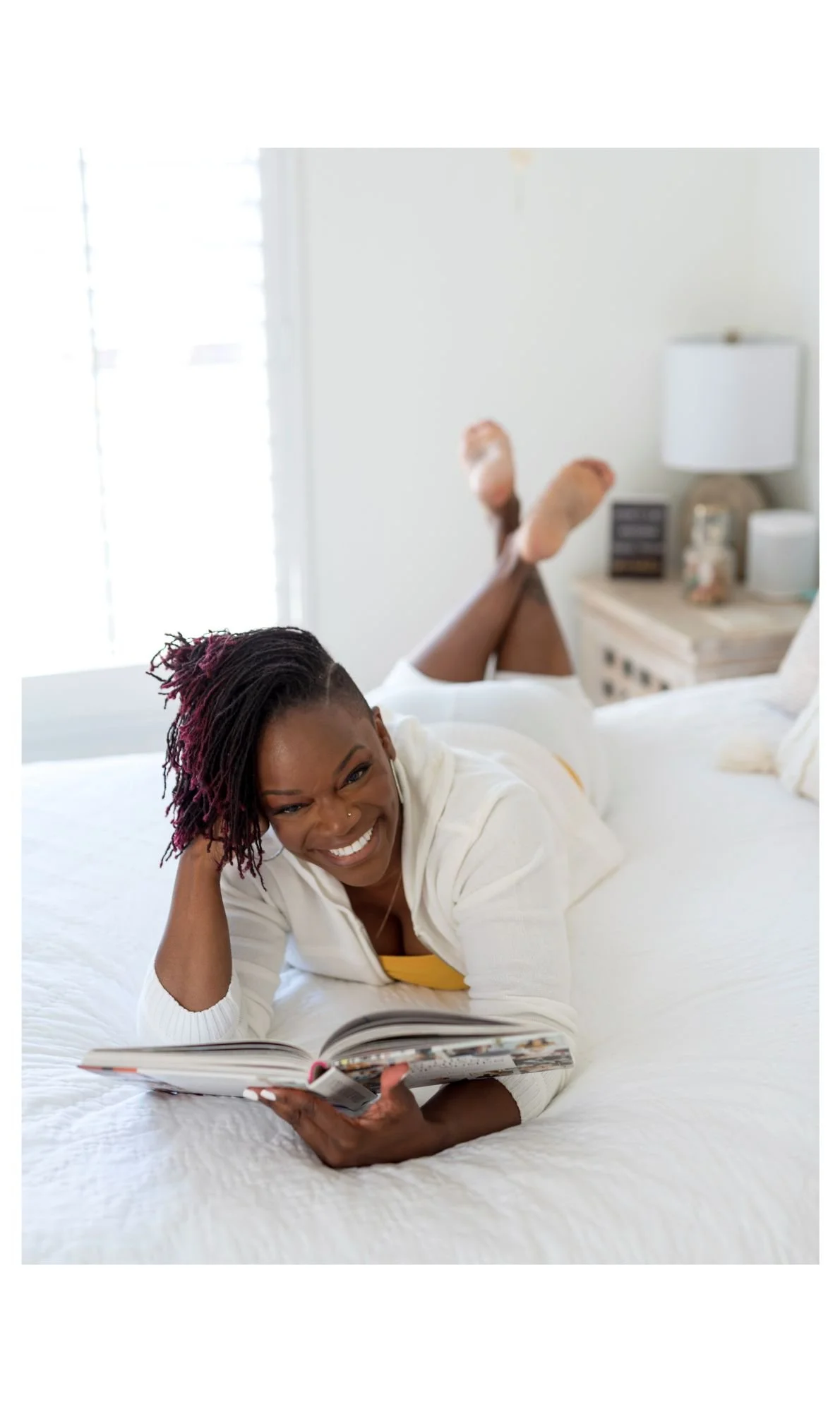 Life coach smiling with a book open on the bed, San Diego personal branding photoshoot