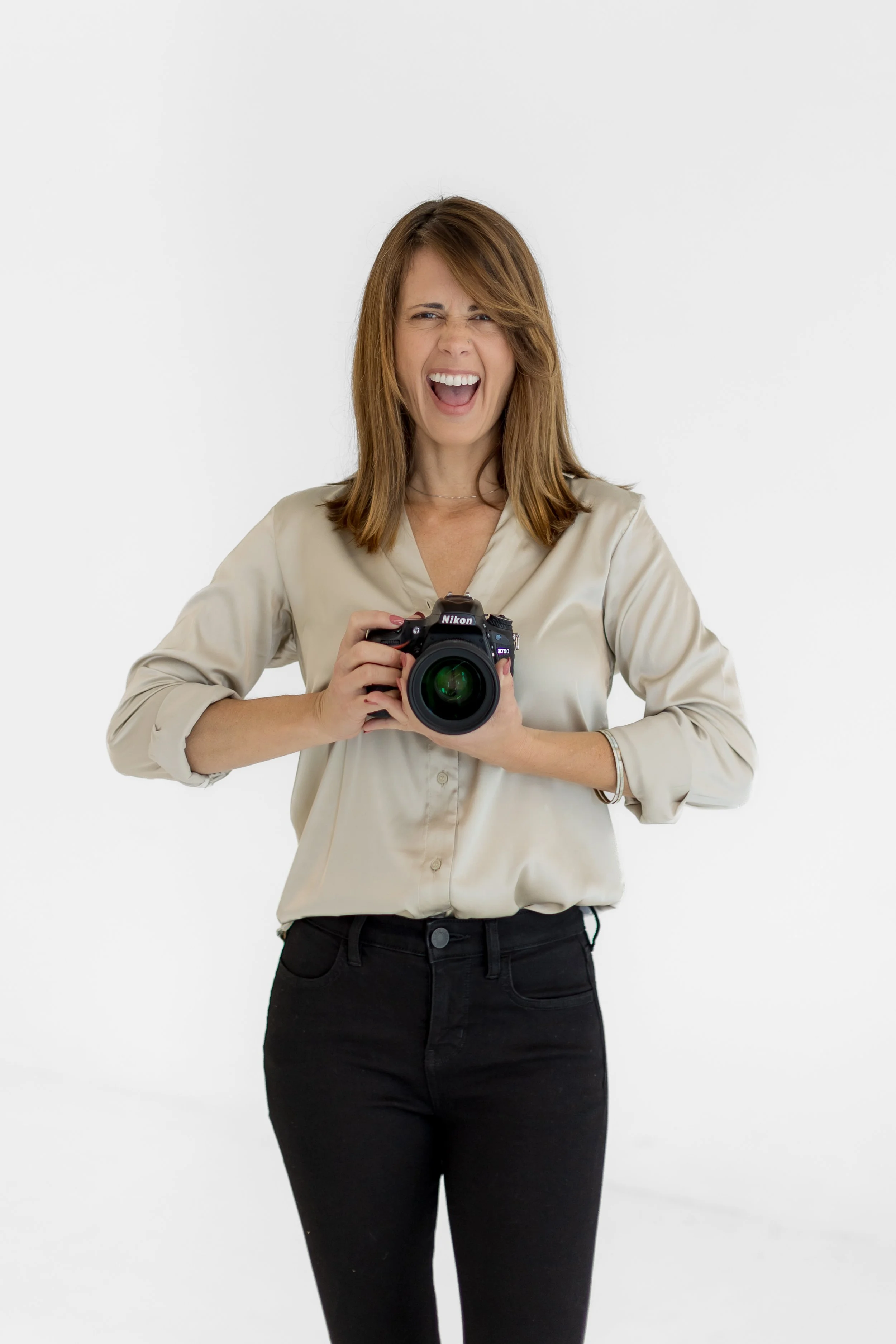 Carina Fleckner, personal branding photographer based in San Diego, smiling and holding her camera