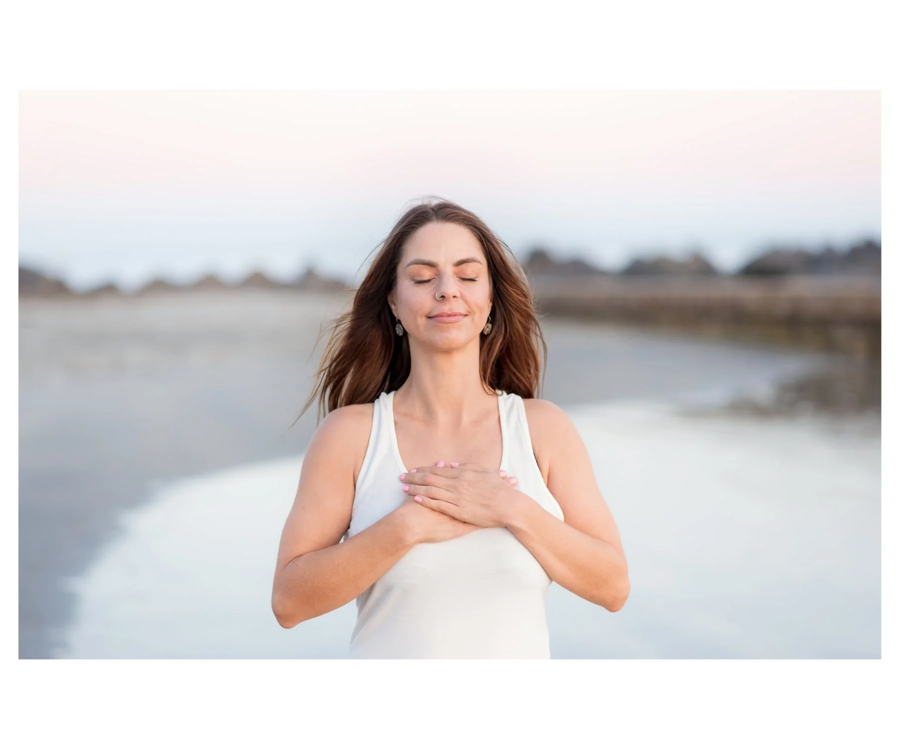 Woman standing peacefully on Coronado beach with her eyes closed and hands on her chest, San Diego photoshoot