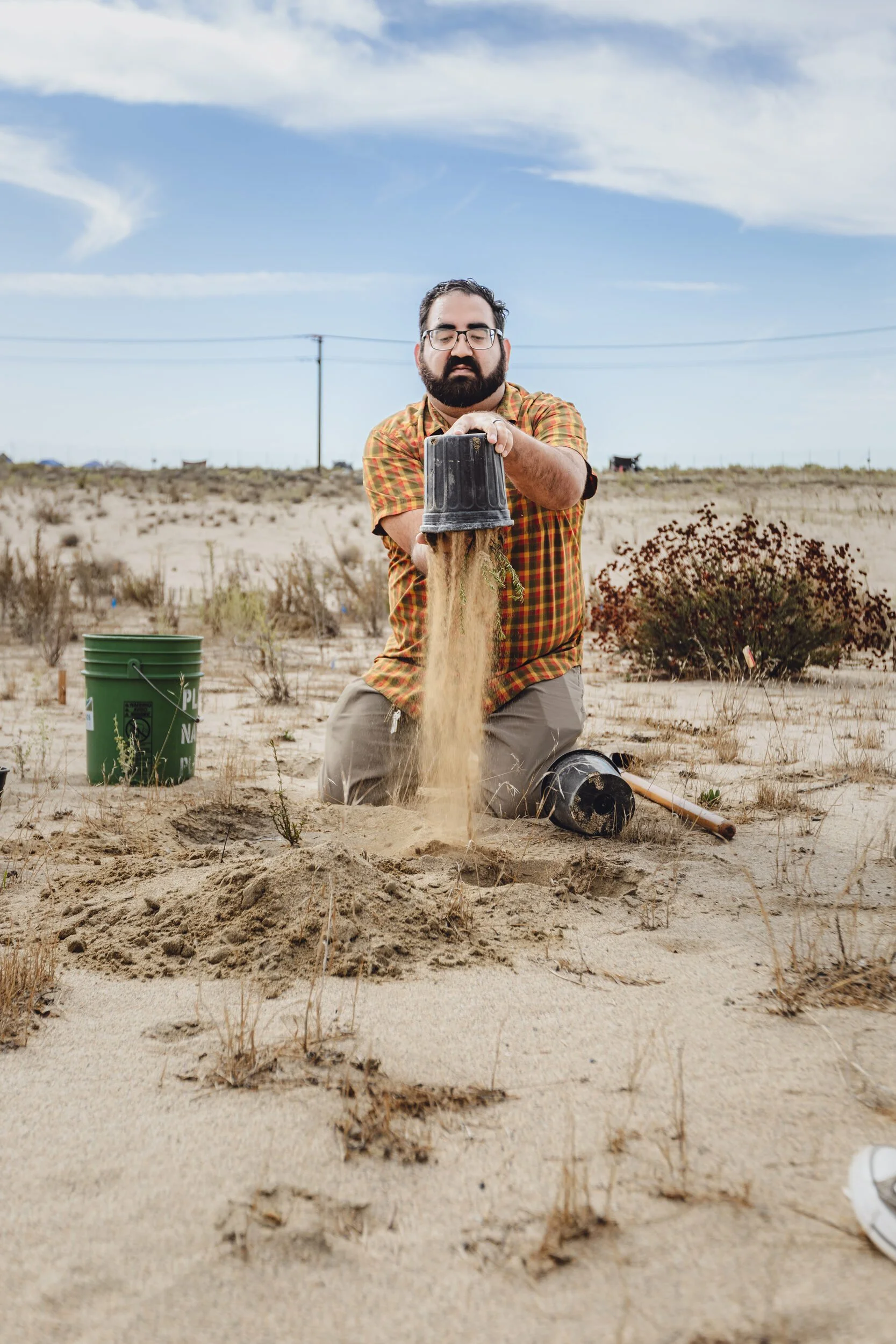 Michael Viramontes, Stewardship Manager at Rivers and Lands Conservancy, demonstrates how to plant California Buckwheat in the Delhi Sand Dunes in Colton, CA. October 25, 2025.
