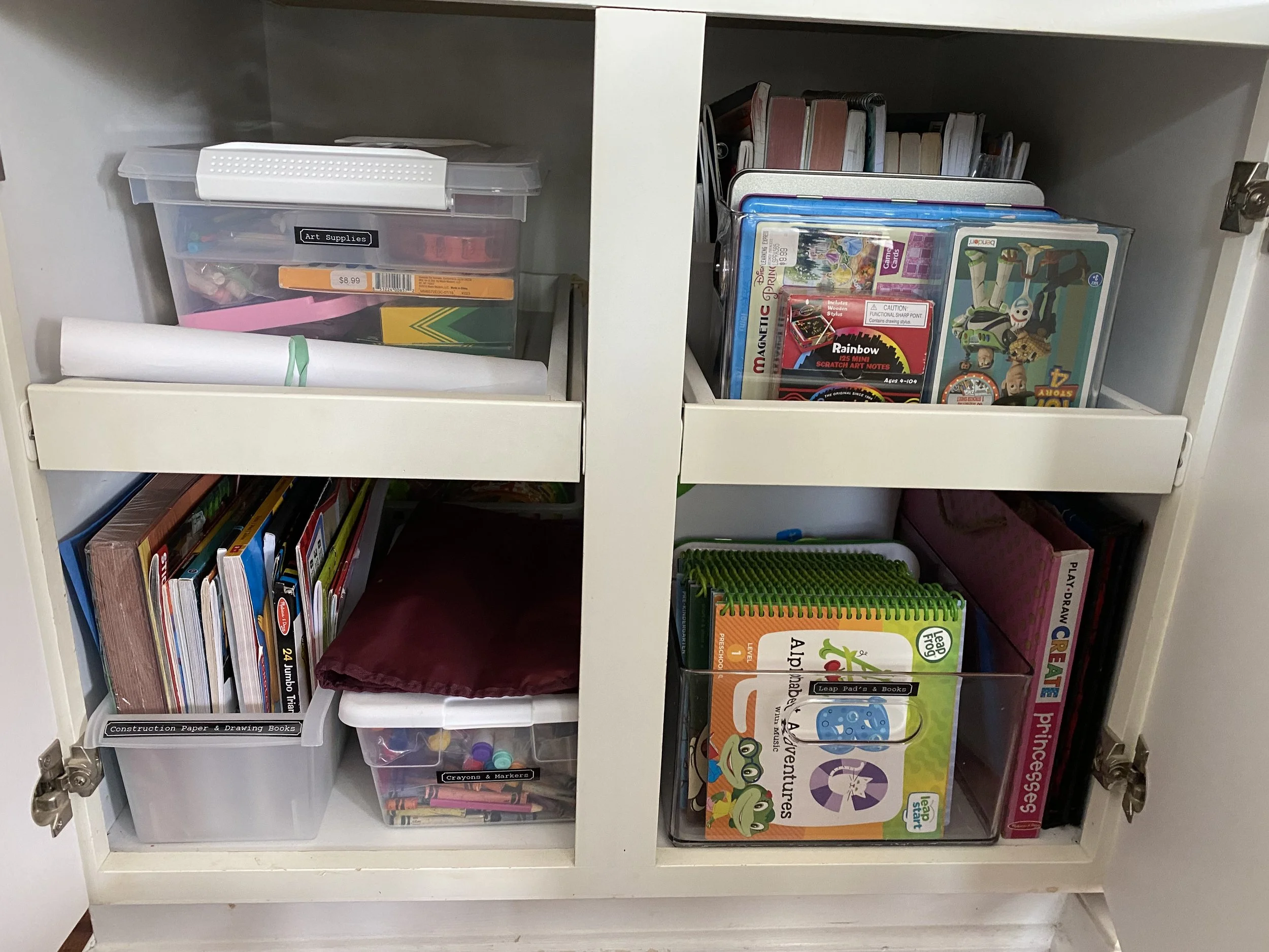 Organized children's books and organized shelves containing art supplies, books, notebooks, and educational materials, including a clear storage containers.