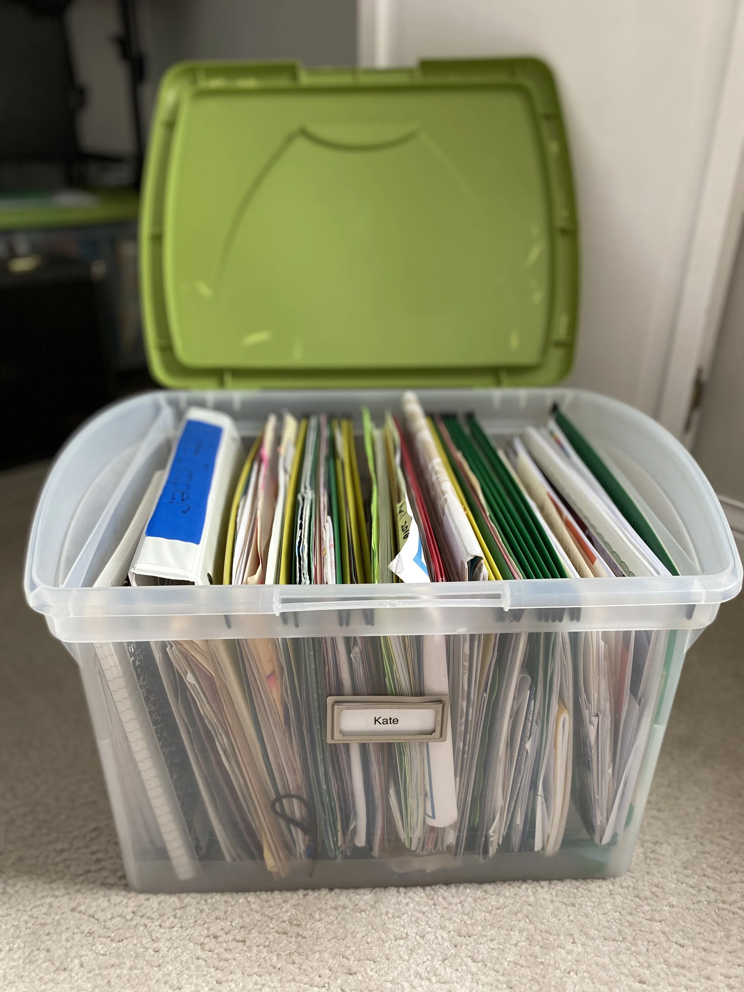 A transparent plastic storage bin filled with various papers and folders, used for organizing paper, documents, bills other desk and closet items