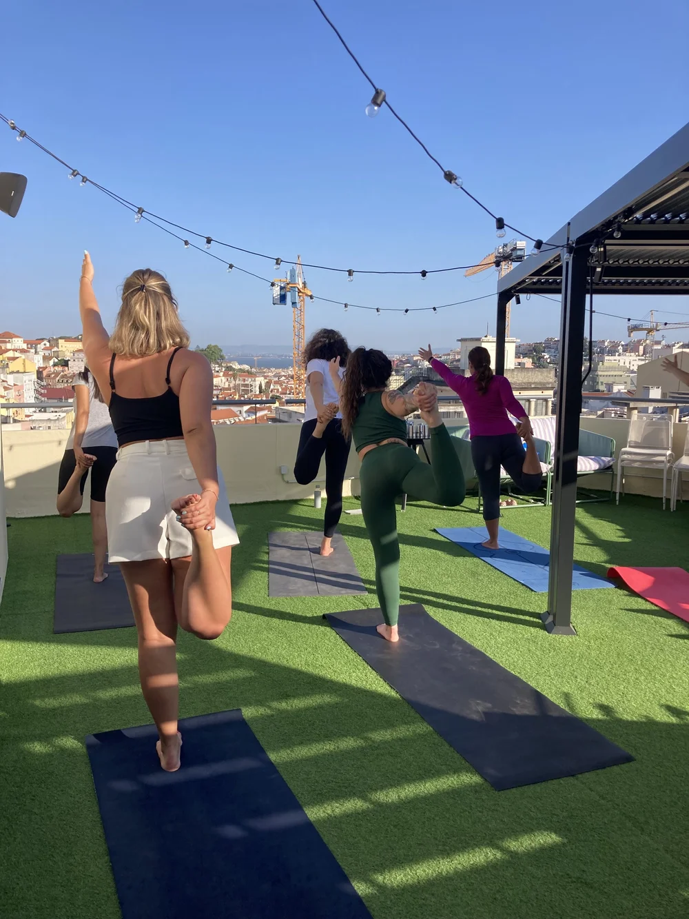 A group balancing in tree pose on a rooftop terrace in Lisbon