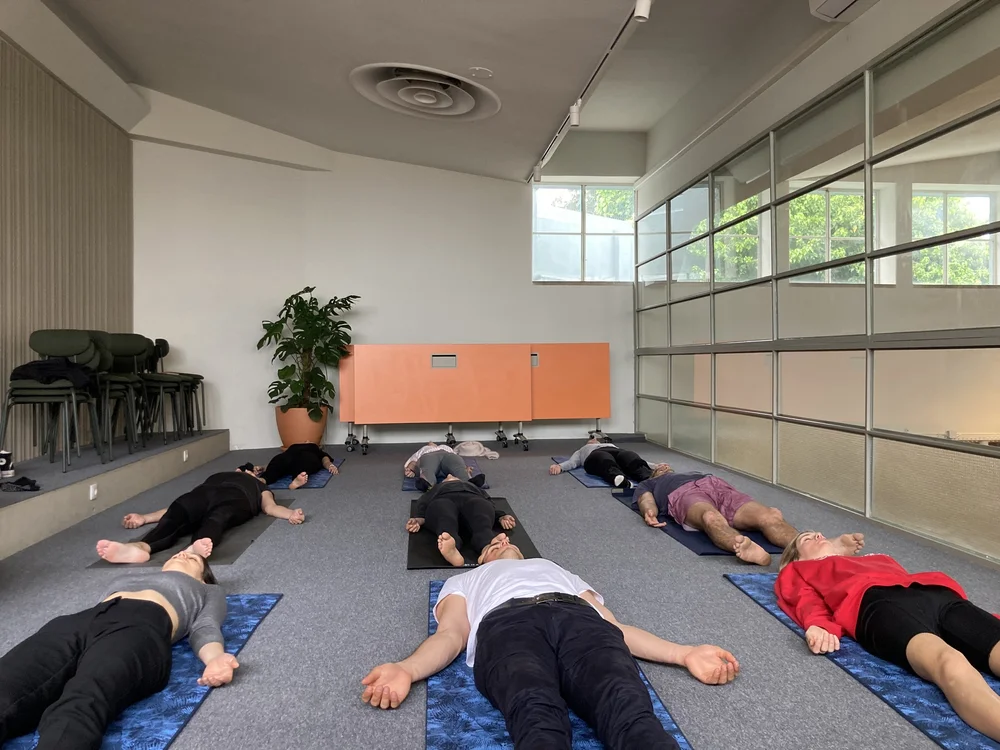 A team resting in savasana on mats in an office studio