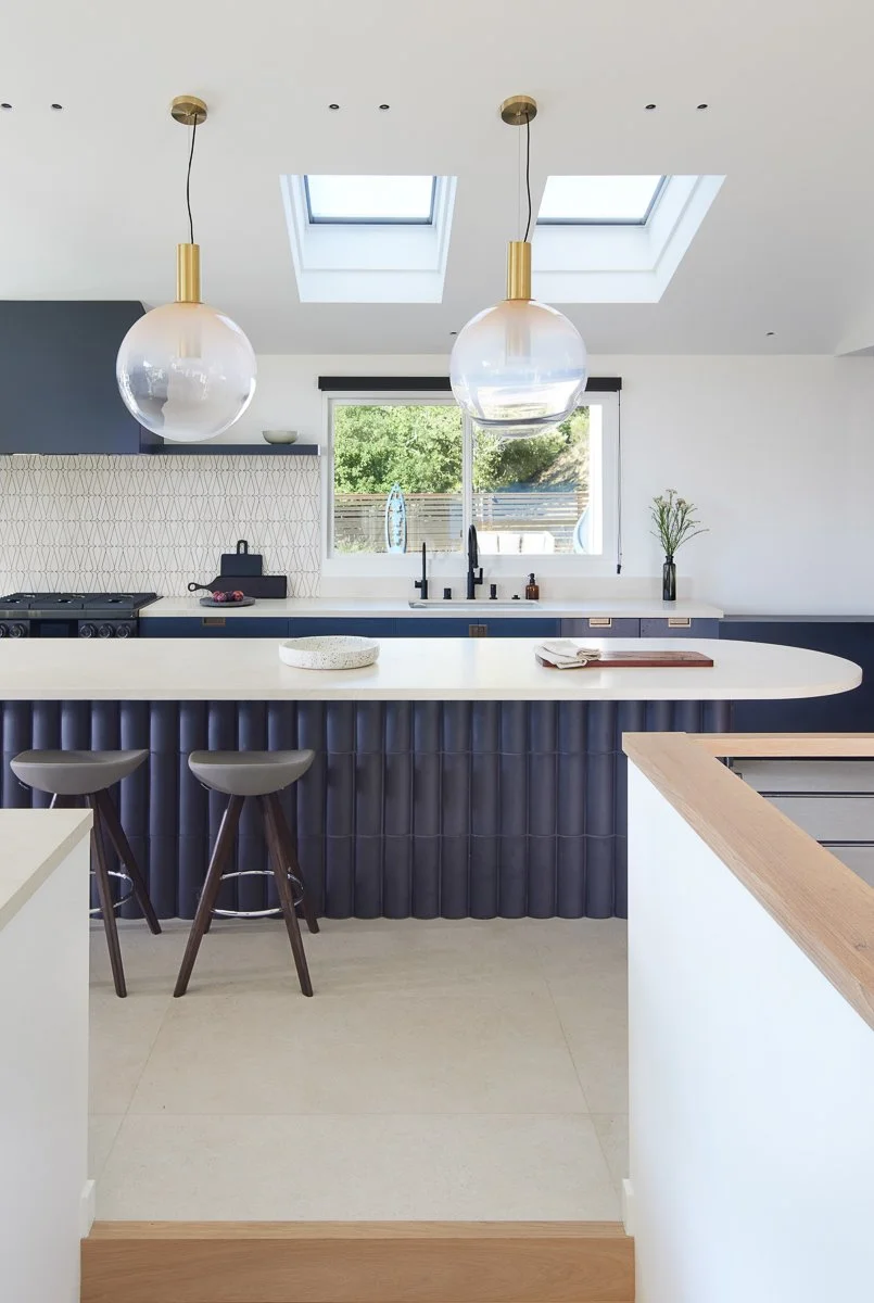 kitchen island counter with bar stools and tile along sink wall with window