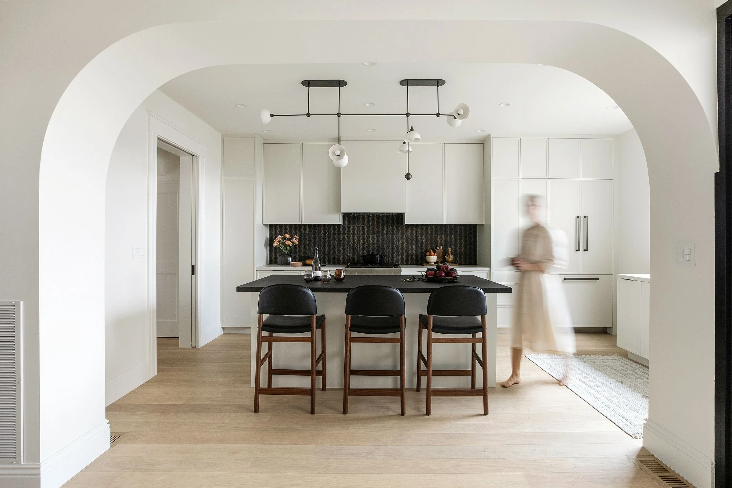 Modern bathroom with a freestanding white bathtub, a black side table and skylights showing green trees outside.