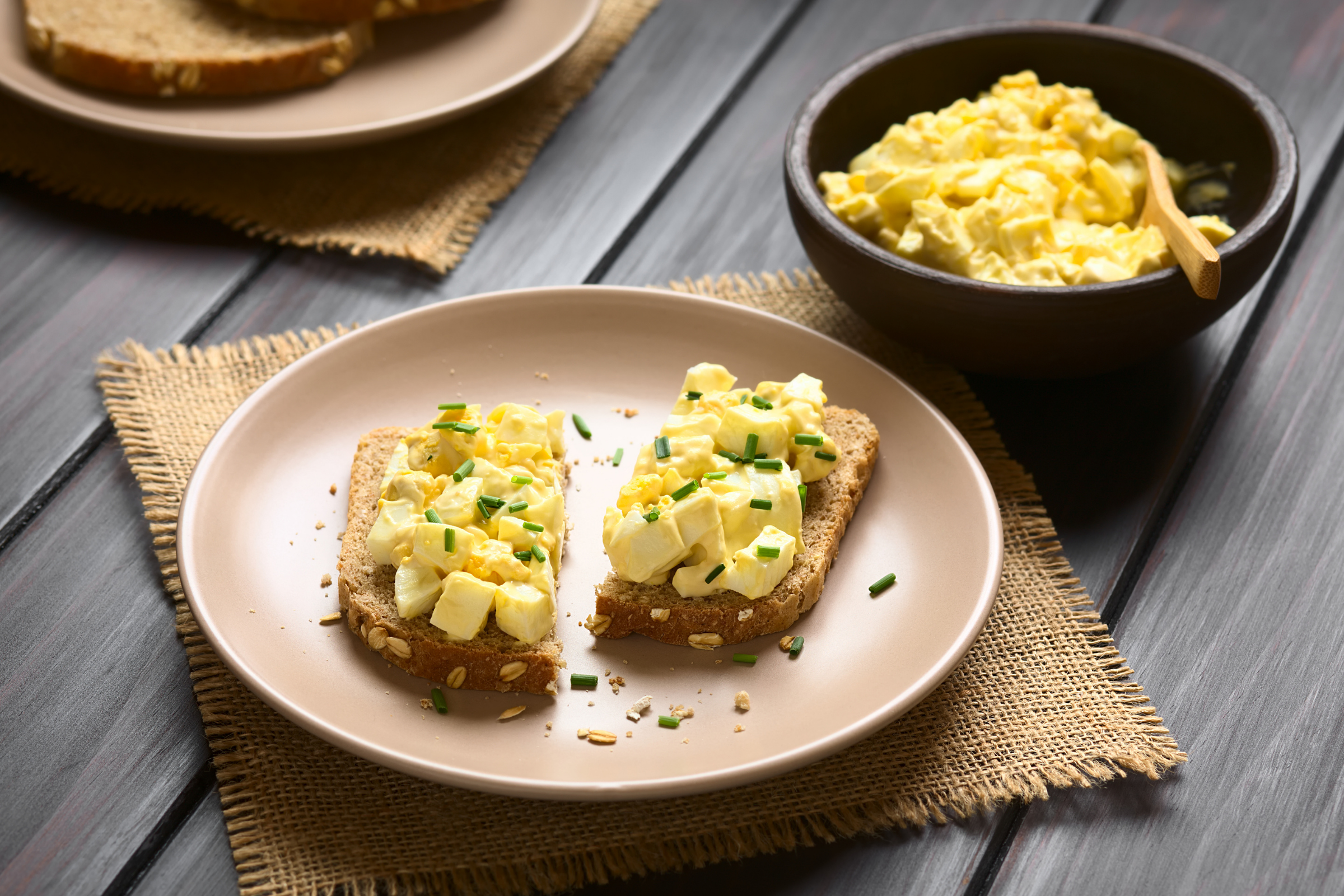 open faced egg salad sandwich on lunch sized plate