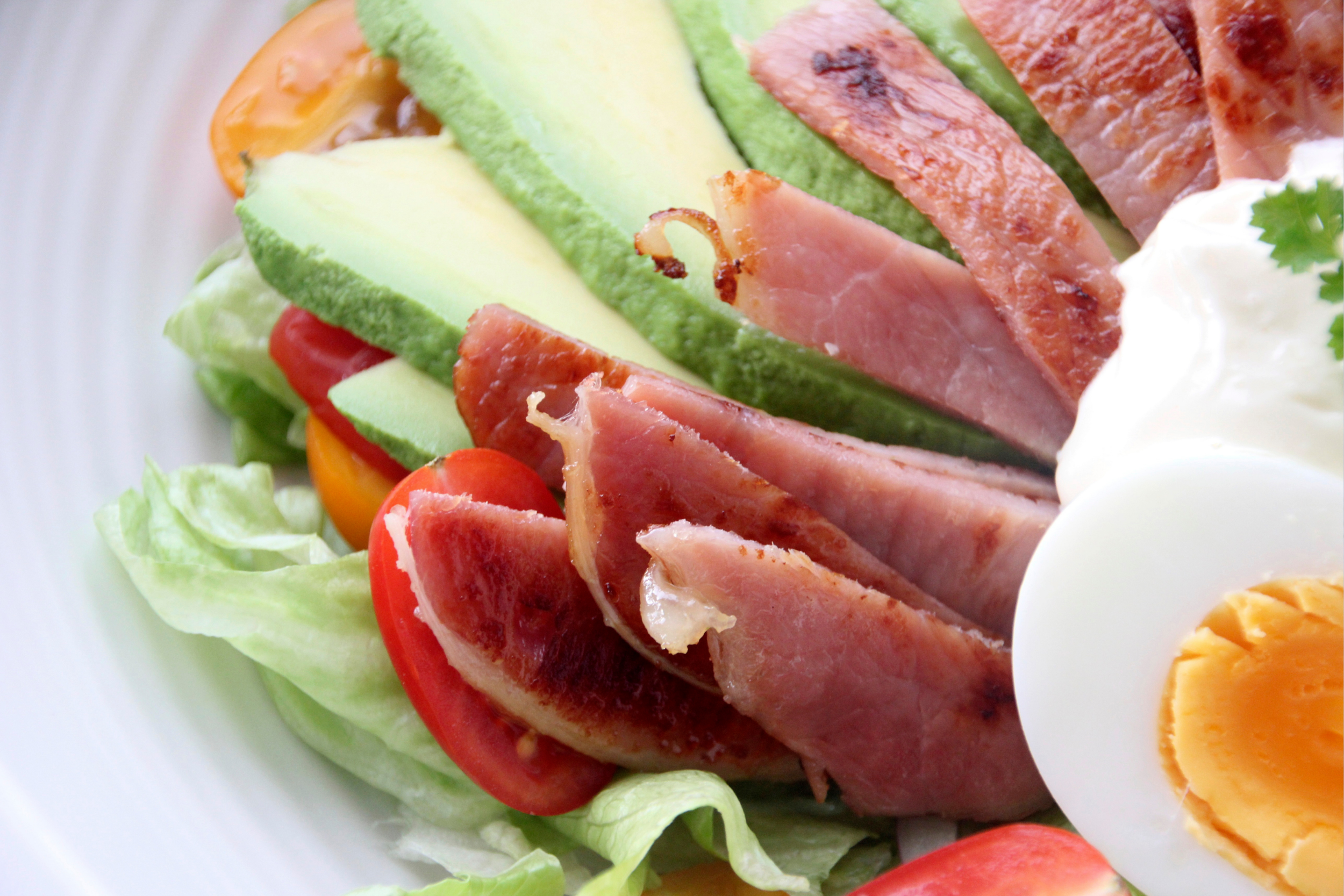 Salad with bacon, lettuce, avocado, soft boiled eggs, and tomatoes