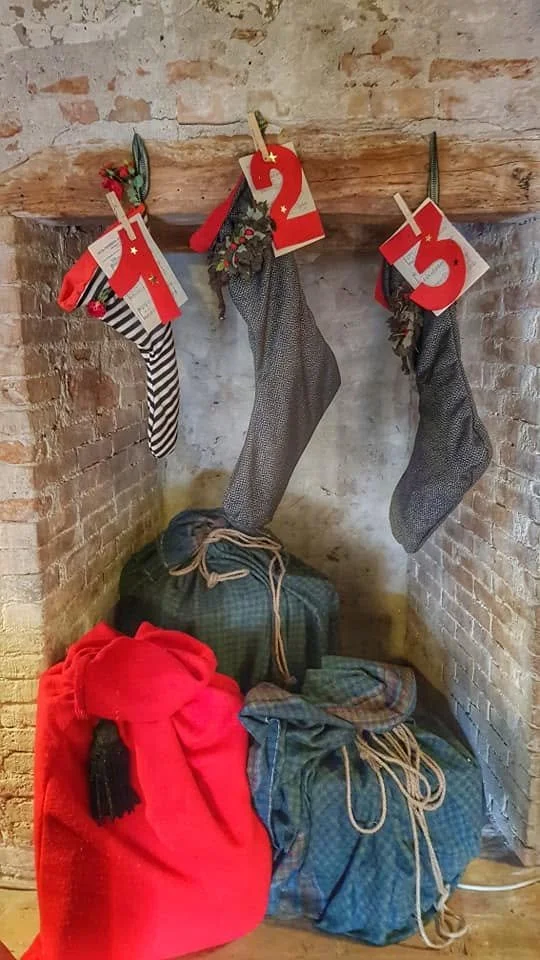 Decorazioni natalizie con calze appese e sacchi decorativi sotto il camino in stile rustico Civico vent8