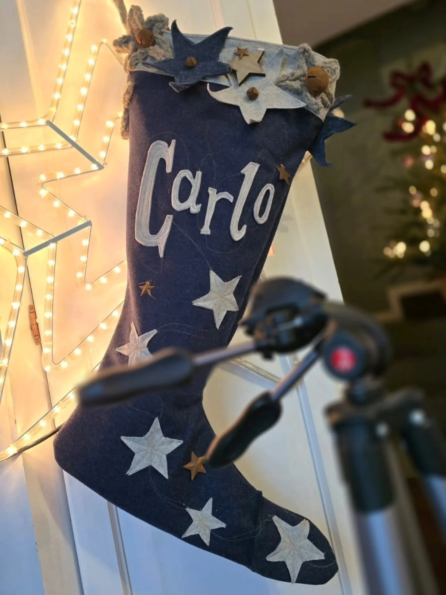 Calza natalizia blu decorate con stelle bianche e orsetti di feltro, con la scritta 'Caro' ricamata, circondata da decorazioni natalizie e luci a led.
