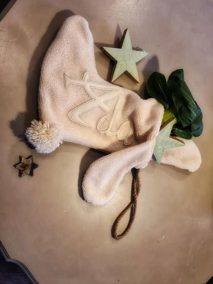 Calze natalizie di pelliccia con decorazioni di stelle di legno e foglie verdi