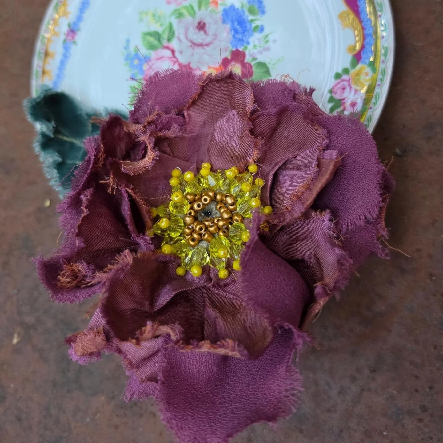 Fiore fatta con tessuti di colore viola, decorato con perline gialle e oro.