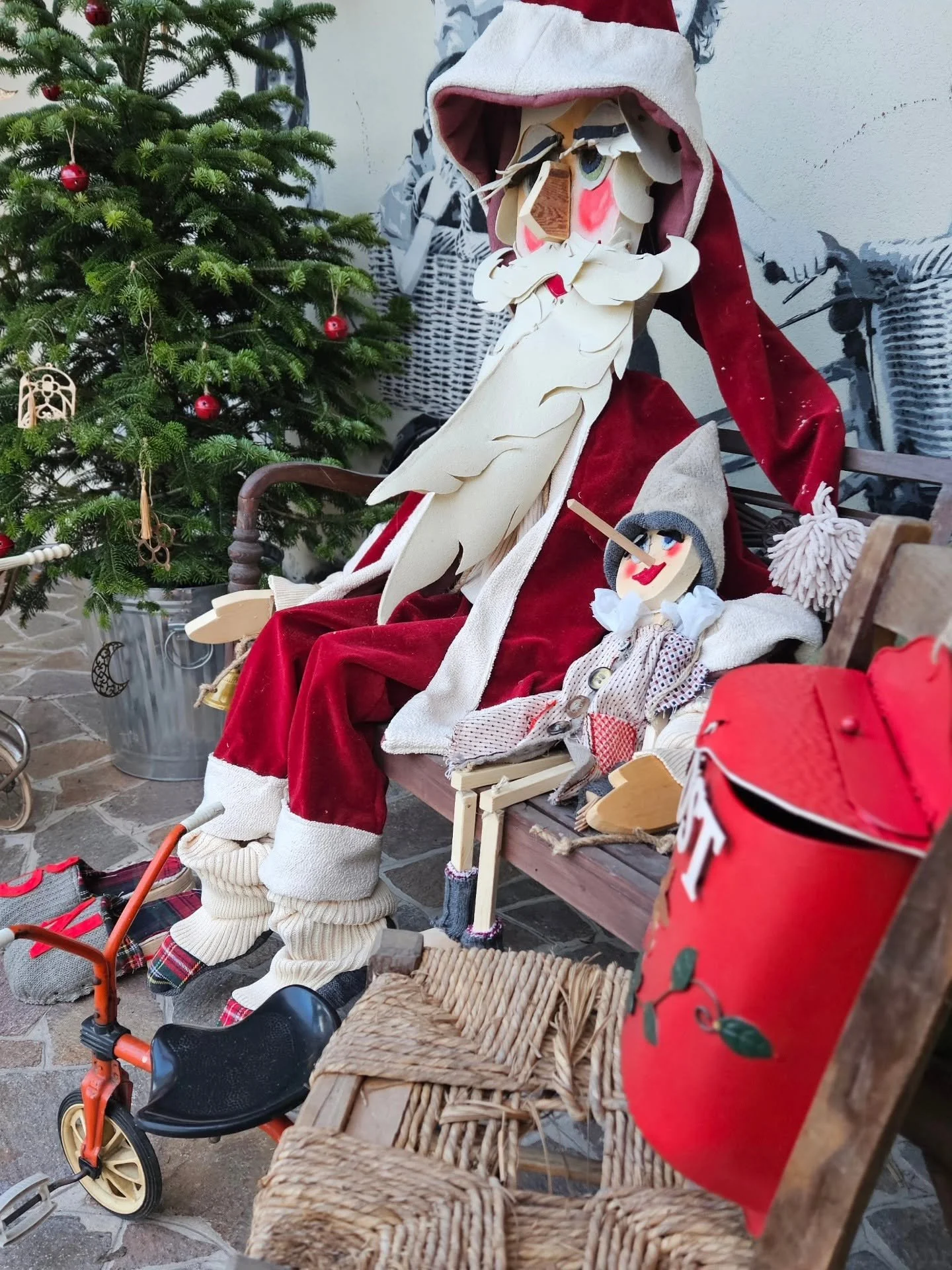 Decorazioni natalizie con bambole e un albero di Natale decorato con palline rosse.