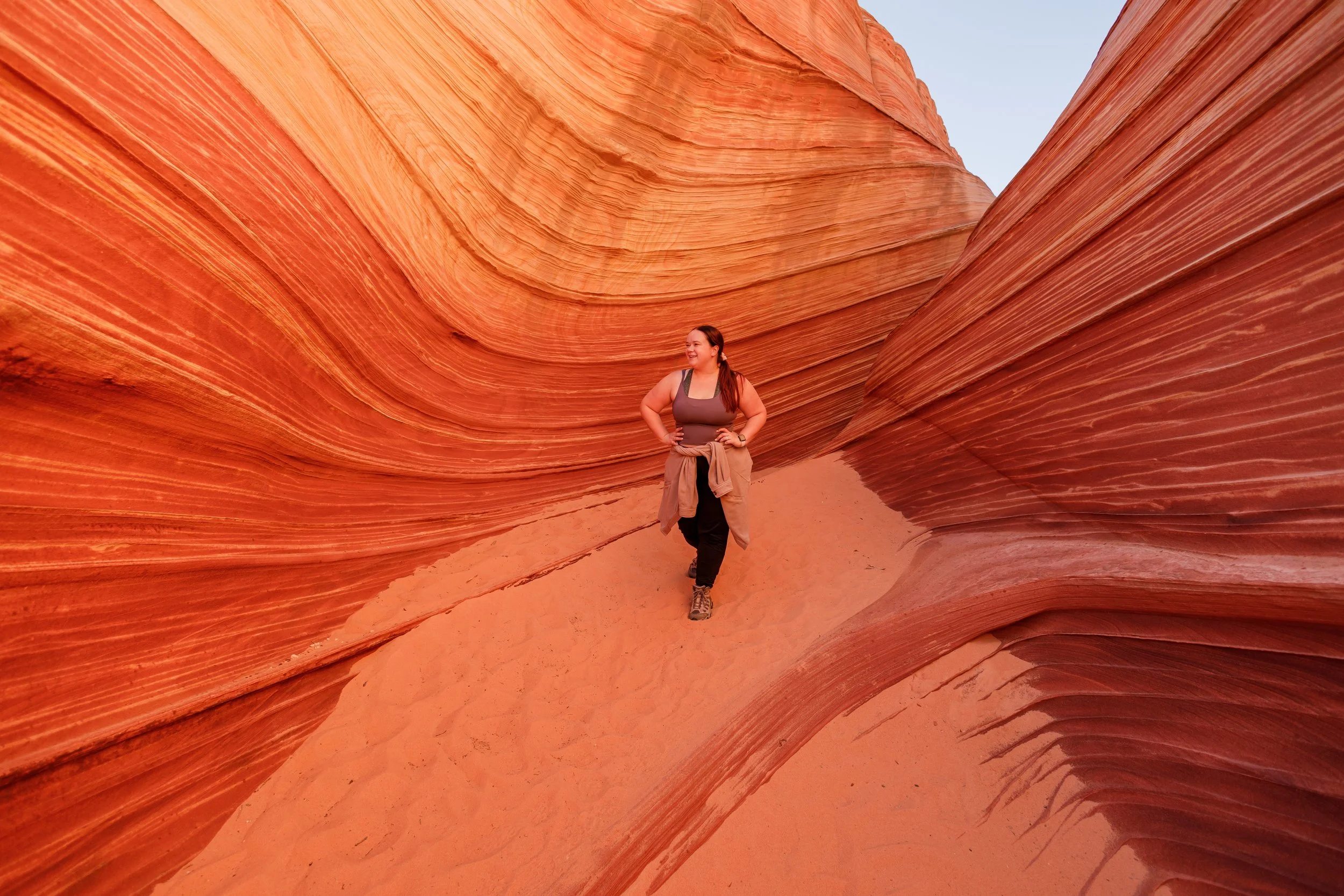 The Wave hike in Utah and Arizona. Woman standing in sand among the rock wave formations in Utah.