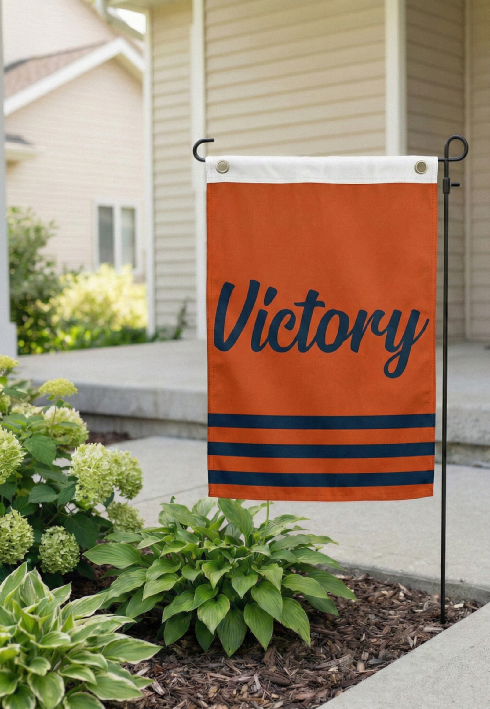 Orange Garden Size Victory Flag [placed in a sunny front yard / among autumn leaves] with navy script.