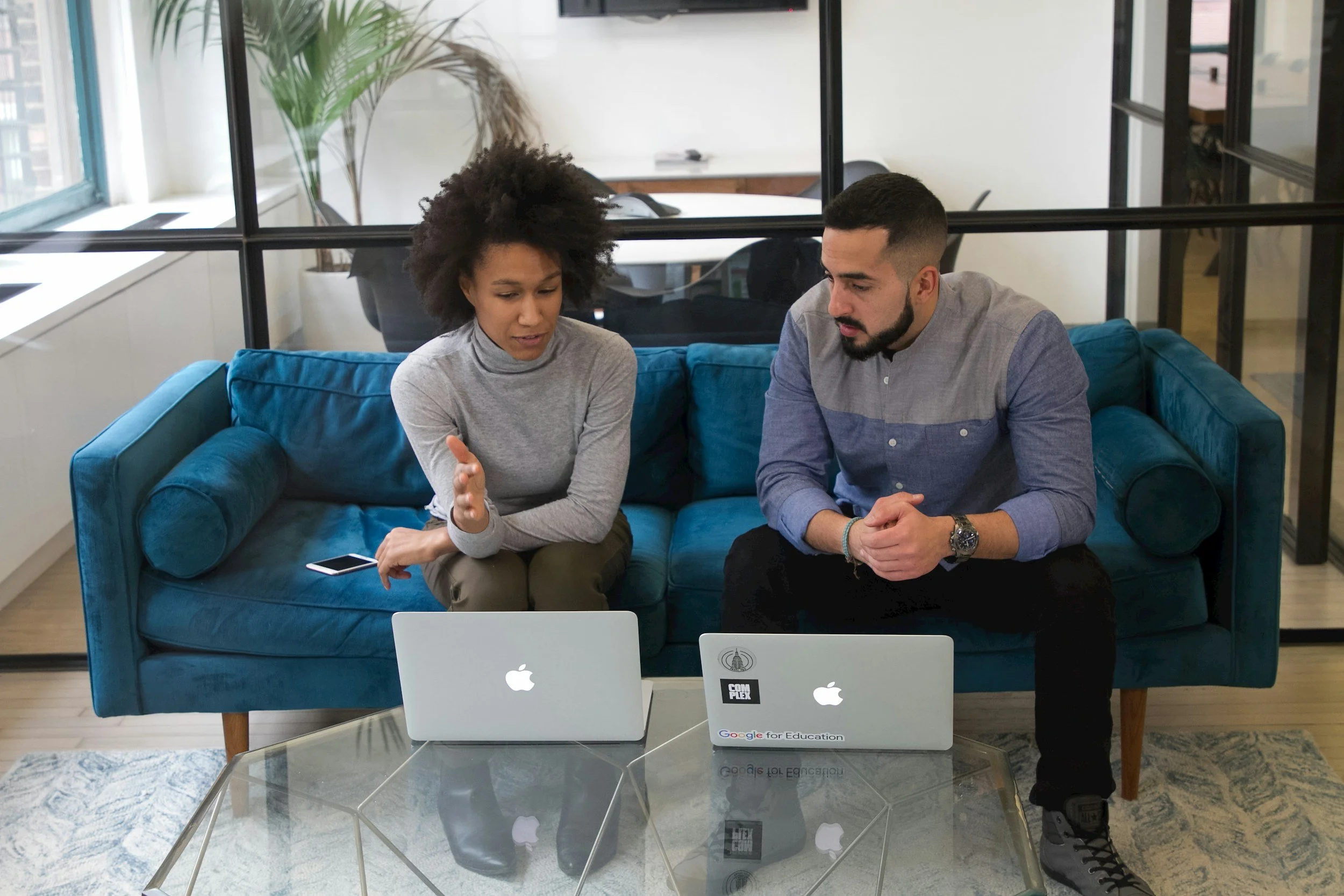 Man and woman sitting on sofa with computers open. One on one work meeting.