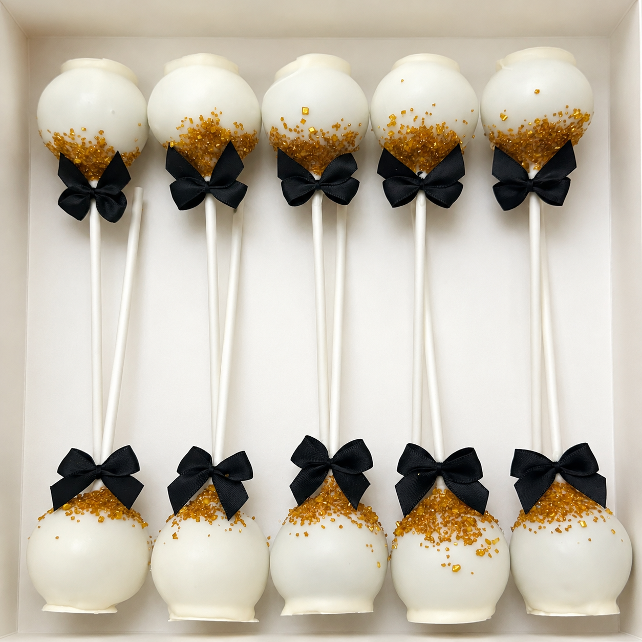 Black, white, and gold elegant graduation cake pops in box