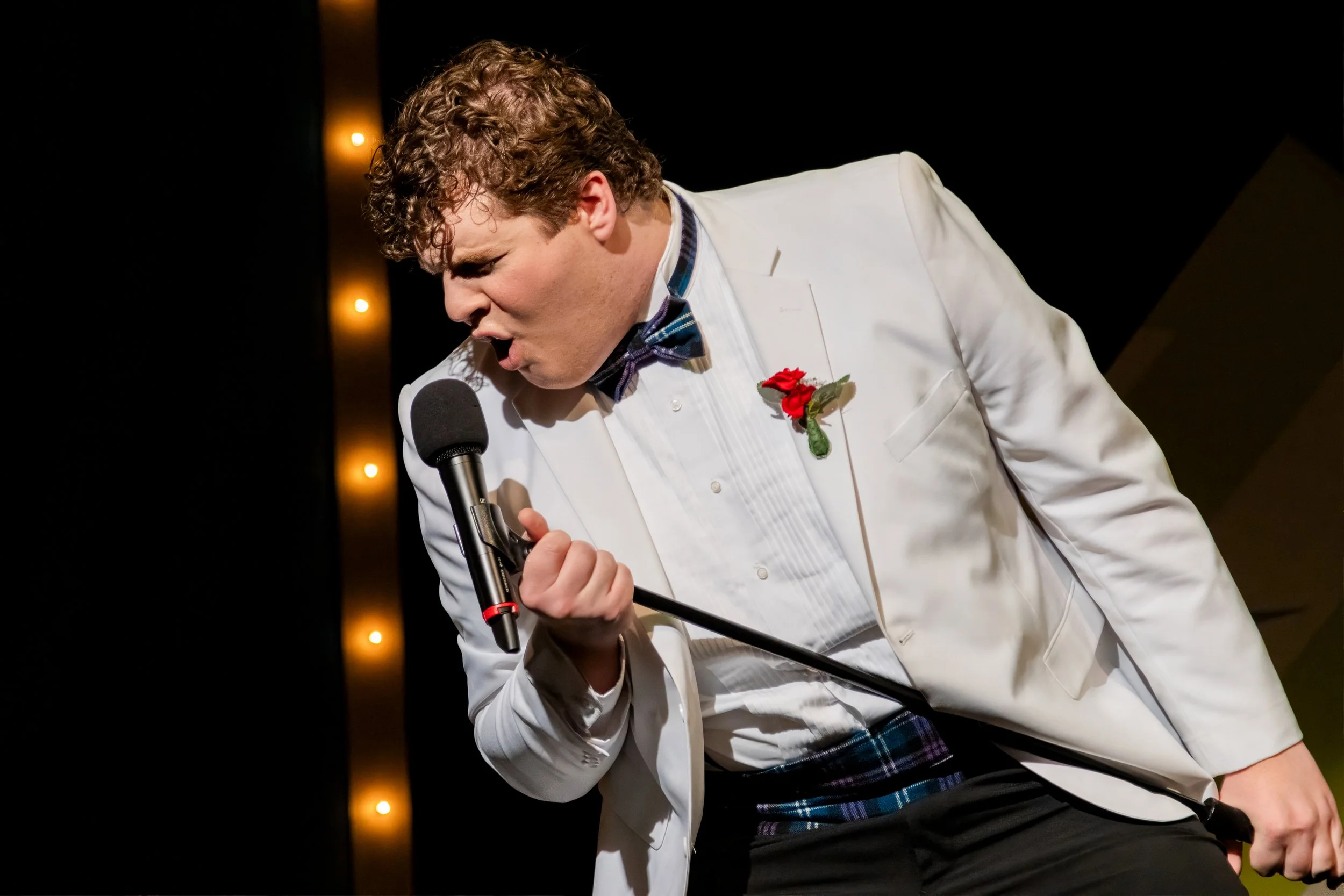 Forever Plaid performer singing in a white dinner jacket.