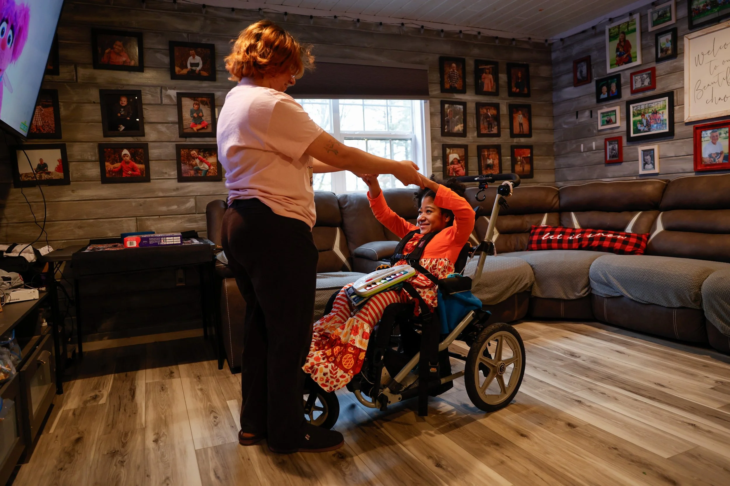 Madelaine Burman, Shelly’s oldest daughter who doubles as a caregiver and teaching assistant at the home, plays with Catie Jane Burman, 10, while she watches television on Tuesday, Nov. 18, 2025, at the Burman homestead in Austin.