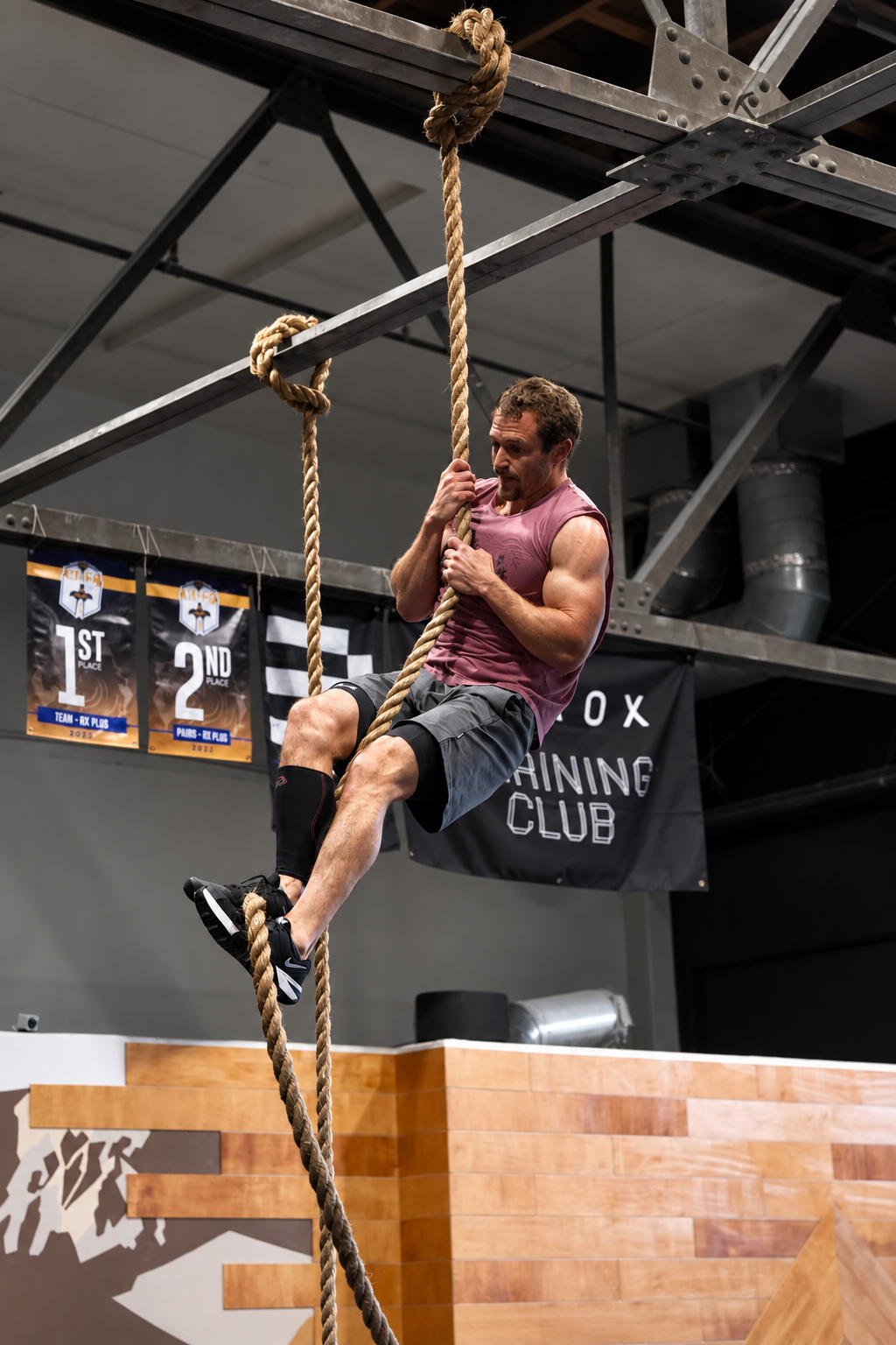 Muscular Athlete Climbing Rope in CrossFit Gym.png
