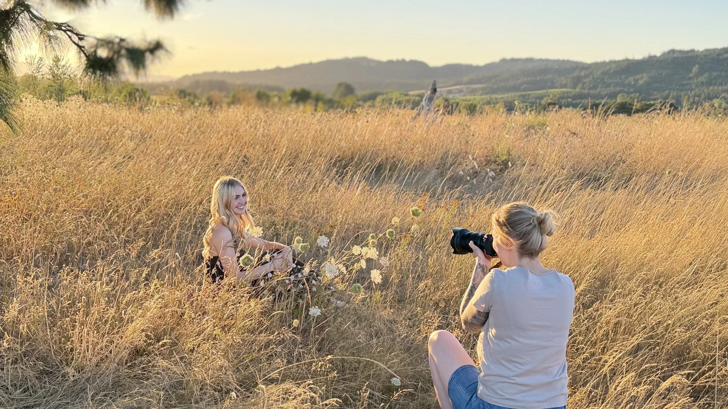 image of woman in a tan shirt and shortstaking a photo of a teen girl in a field of tall dry grass