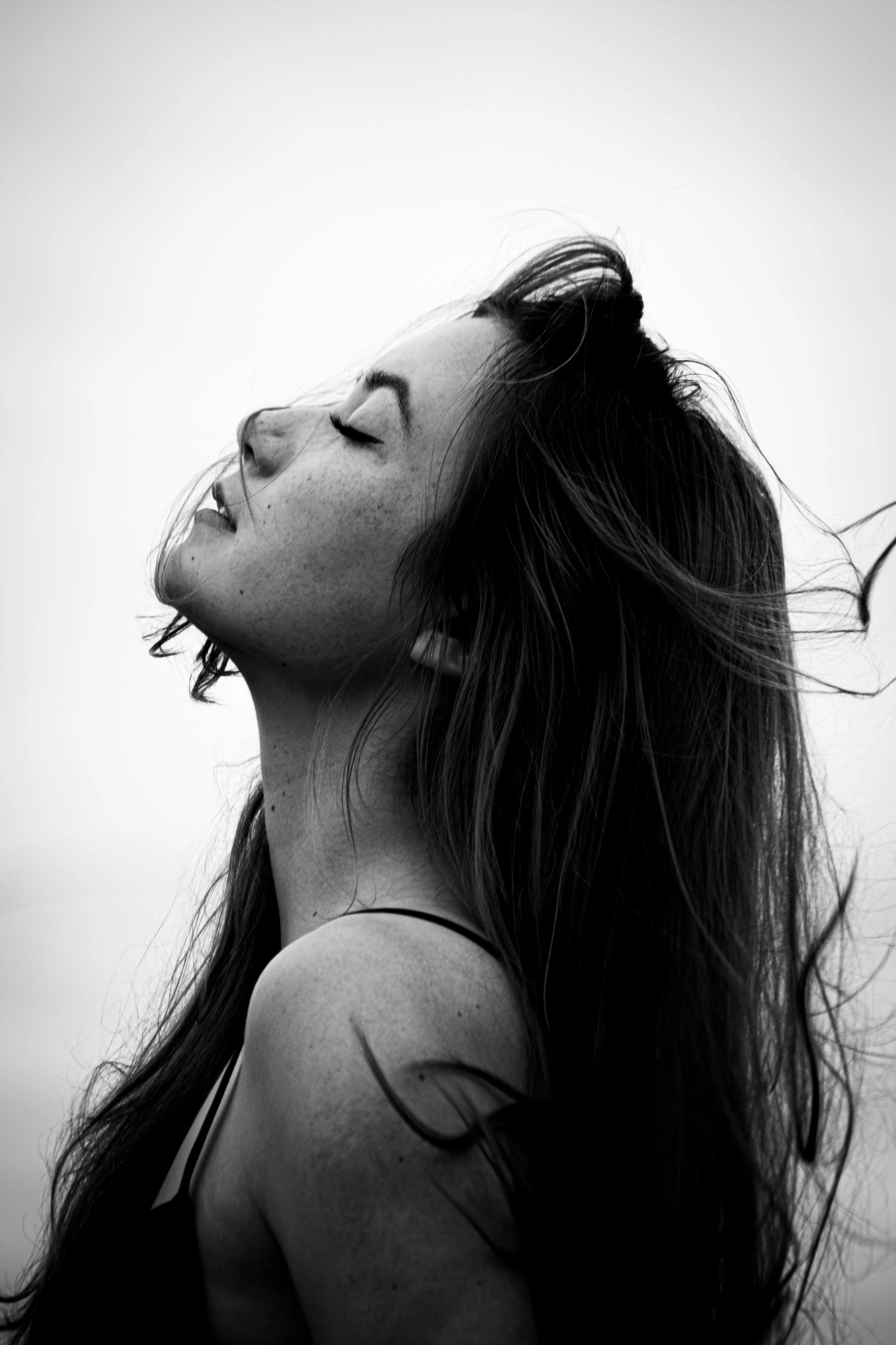 Black and white portrait of a woman with long hair, eyes closed, head tilted back, and a serene expression.